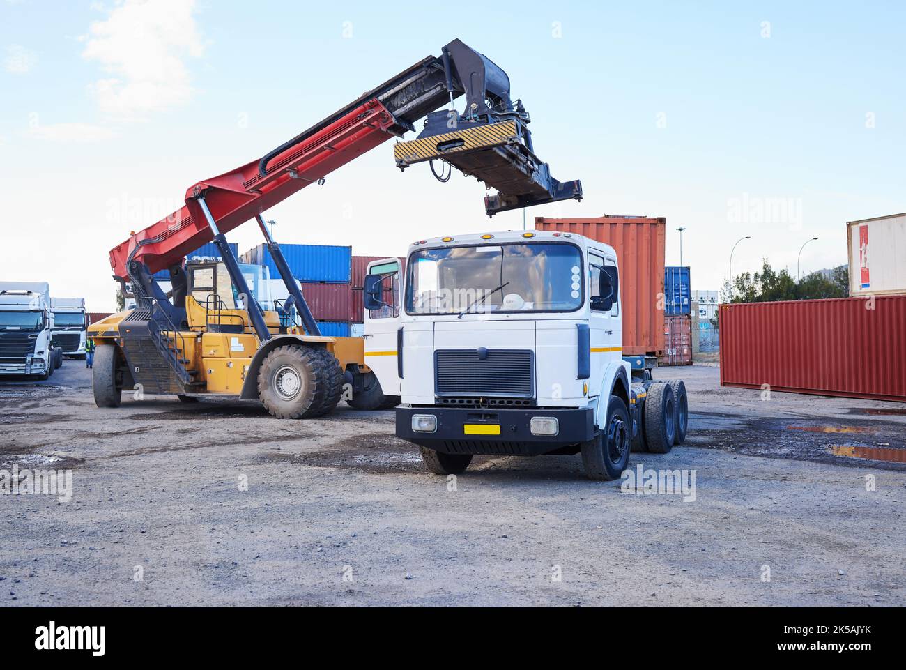 Camion, logistica e supply chain con un conducente di costruzione su un cantiere di container commerciale per la spedizione o la distribuzione. Stoccaggio, stoccaggio e carico Foto Stock