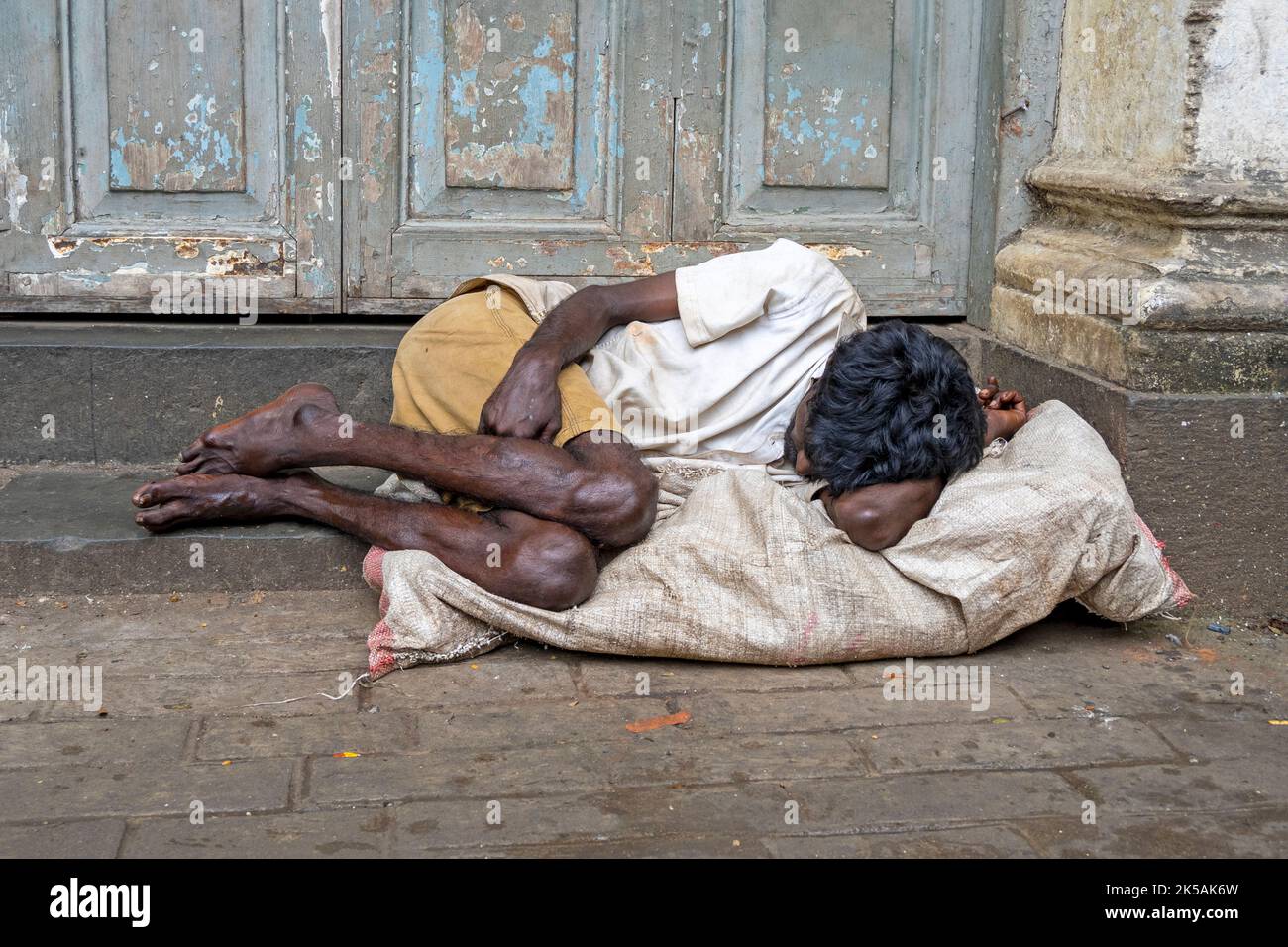MUMBAI - SET 26: Beggar senzatetto uomo che si posa sul marciapiede a Mumbai, il 26 settembre. 2022 in India Foto Stock