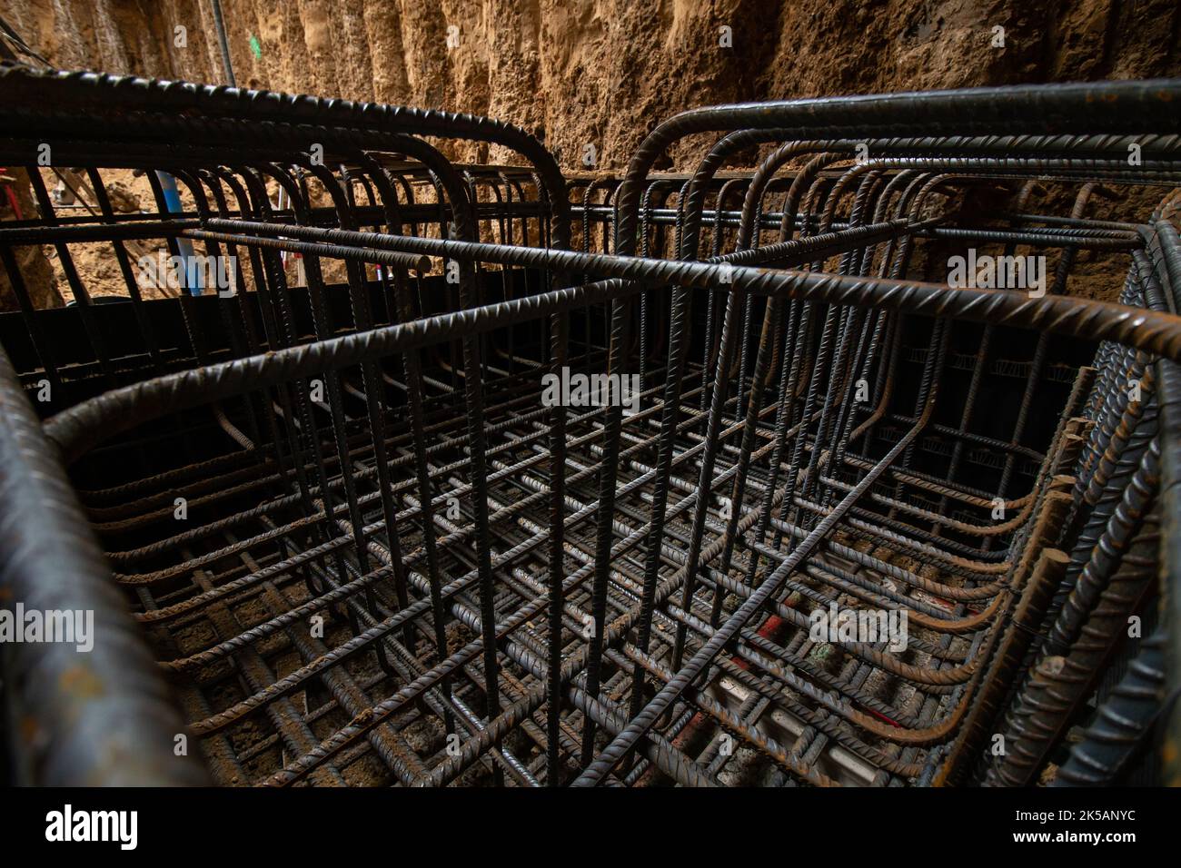 Gabbia di rinforzo-armatura di pozzo in terreno sabbioso in scavo seminterrato per fondazione di zattere in cemento armato Foto Stock