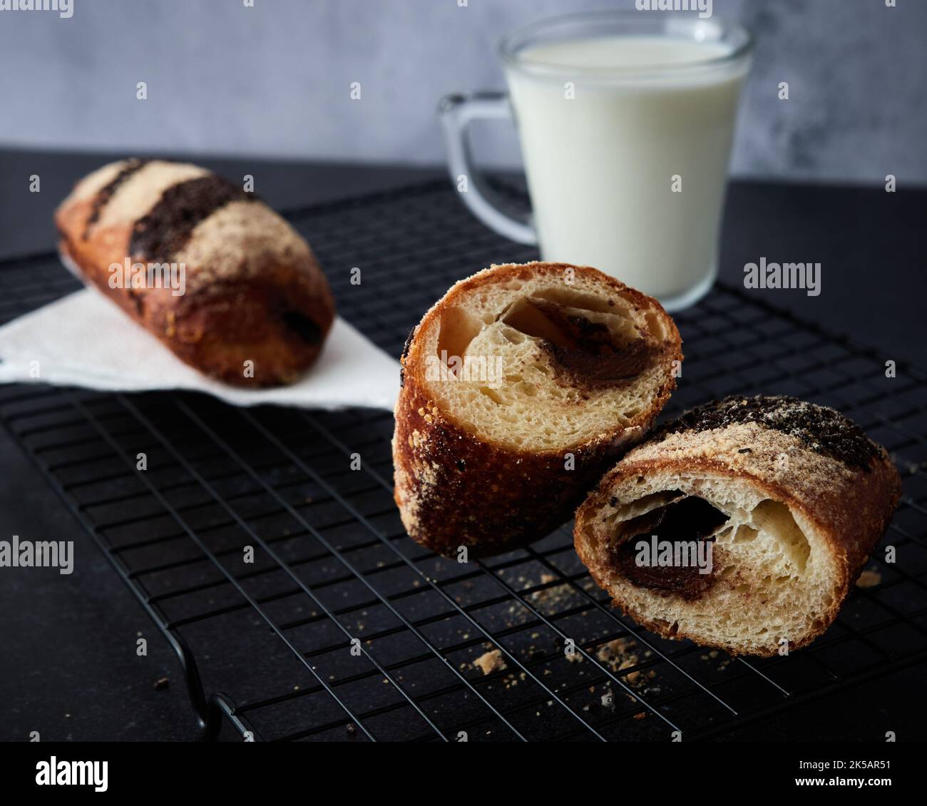 Un primo piano di panino con crema al cioccolato e un bicchiere di latte sullo sfondo. Foto Stock