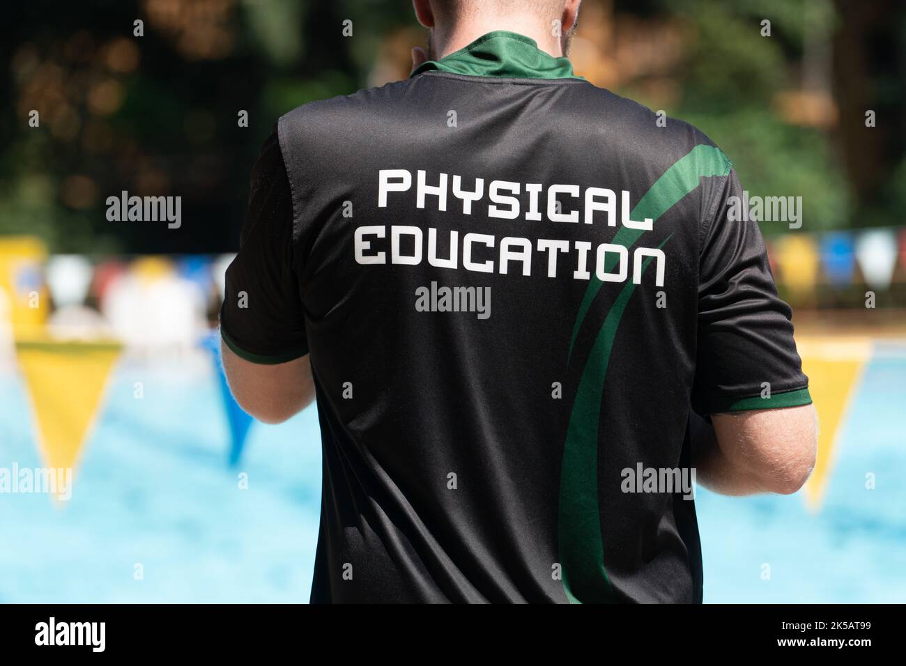 Vista posteriore del pulmann da nuoto, indossando una maglietta EDUCATIVA FISICA, lavorando in una piscina esterna Foto Stock