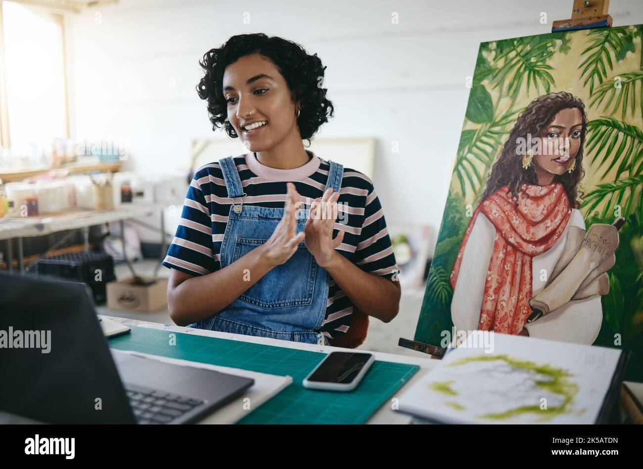 Videoconferenza, presentazione e pittore che parla della sua pittura su chiamata con un computer nel suo studio di lavoro. Artista, designer e pittore indiano Foto Stock