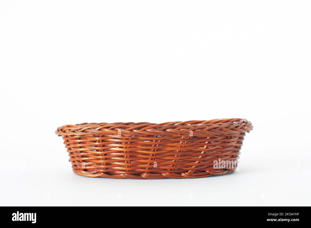 Cestino vuoto in vimini di colore legno e marrone isolato su sfondo bianco con messa a fuoco selettiva. Foto Stock