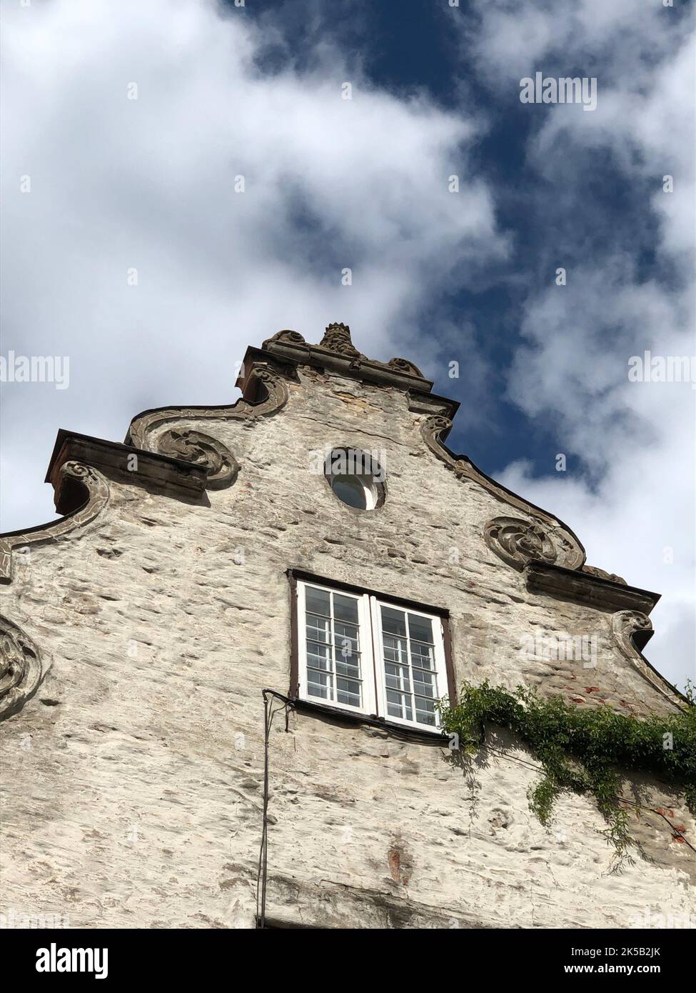 Una parte superiore di un vecchio edificio con un cielo blu nuvoloso sullo sfondo Foto Stock