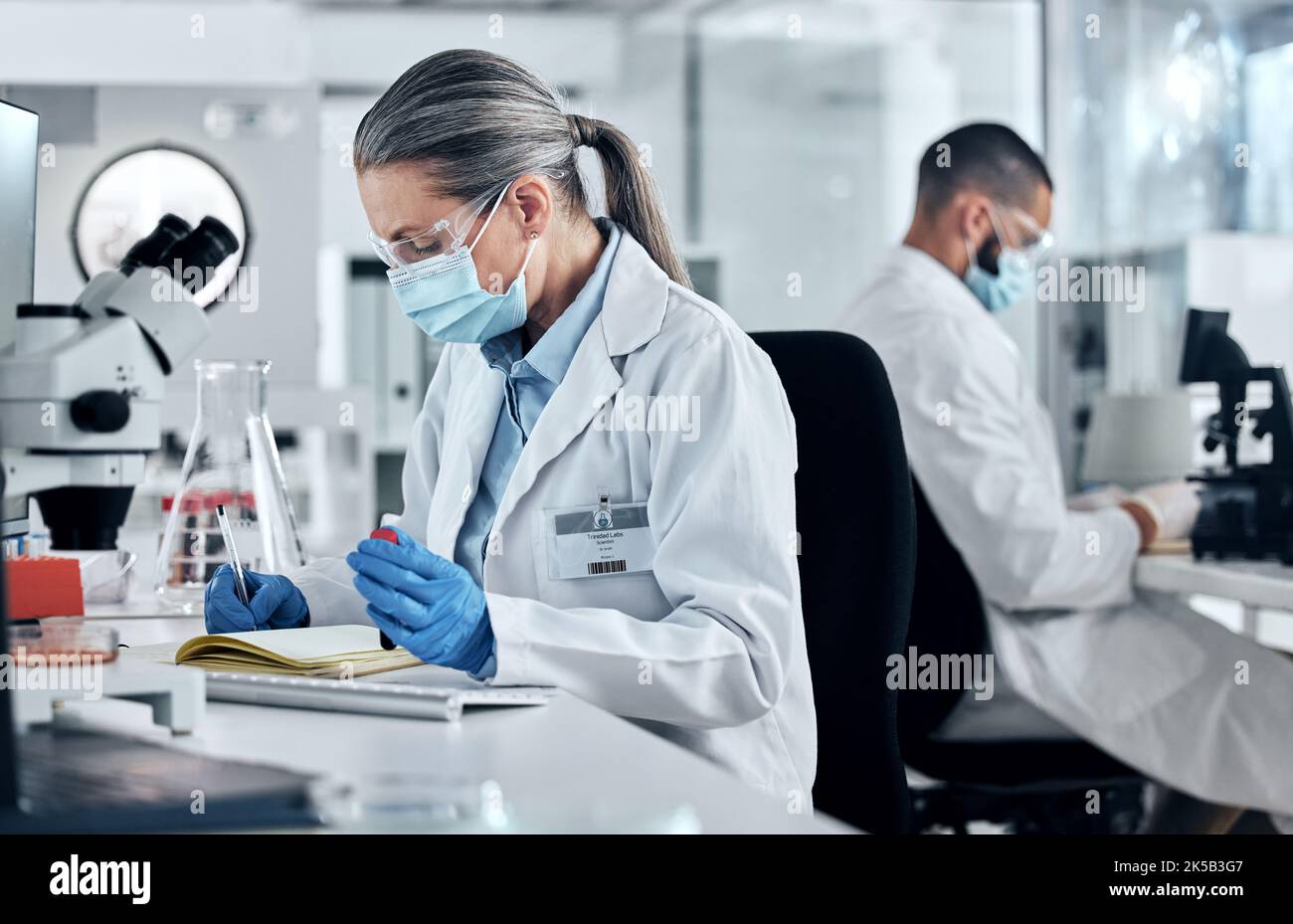 Scienza, sangue di dna e ricerca covid con una donna che scrive in un notebook per l'innovazione e la svolta in un laboratorio. Analisi, tecnologia e medicina Foto Stock