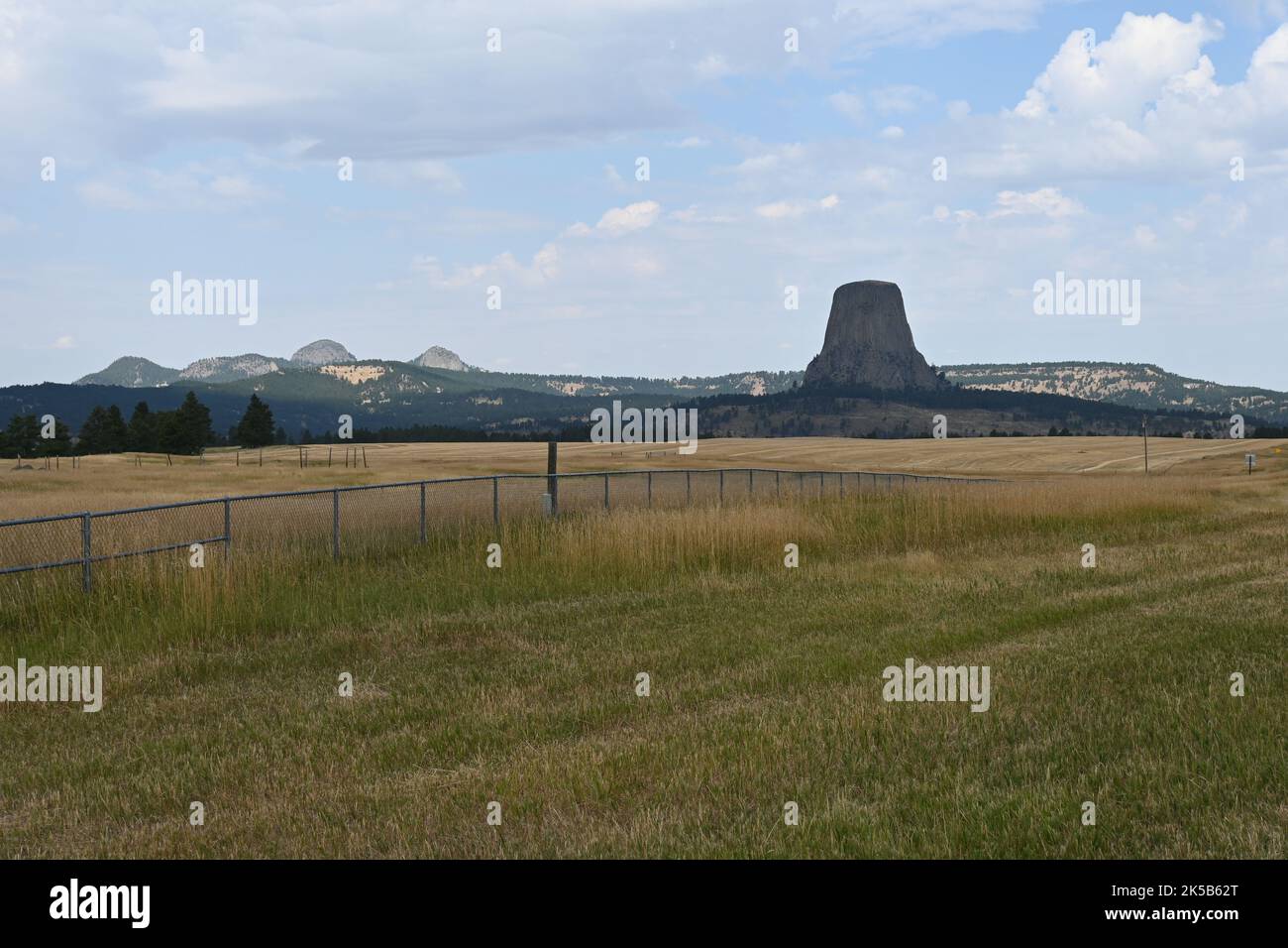 La Devils Tower vista dal verde e giallo prateria nel Wyoming sotto il cielo nuvoloso blu Foto Stock