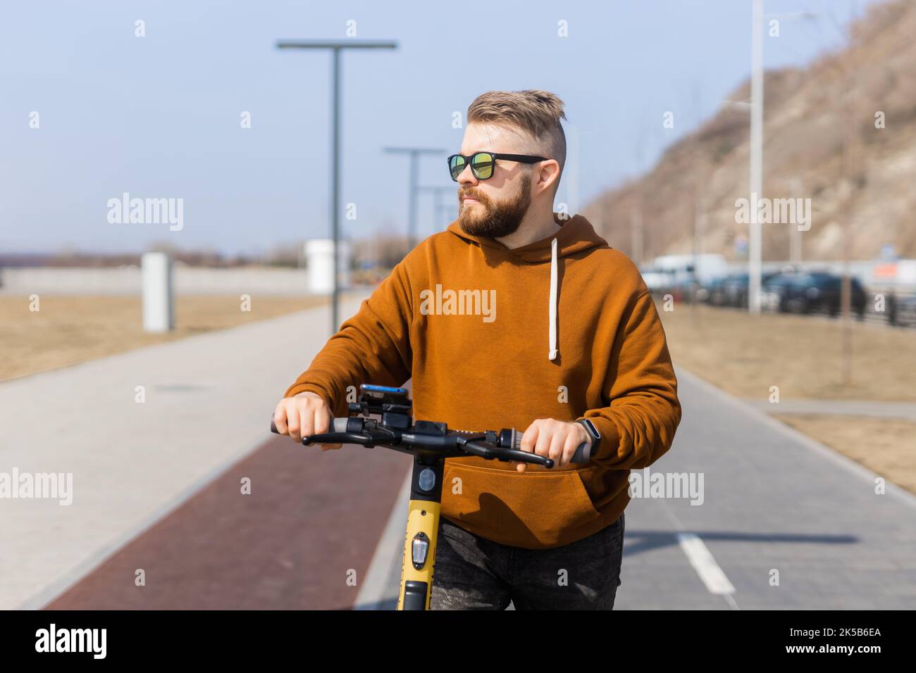 Un uomo moderno che guida in scooter elettrico in città. Concetto innovativo di trasporto e stile di vita. Foto Stock