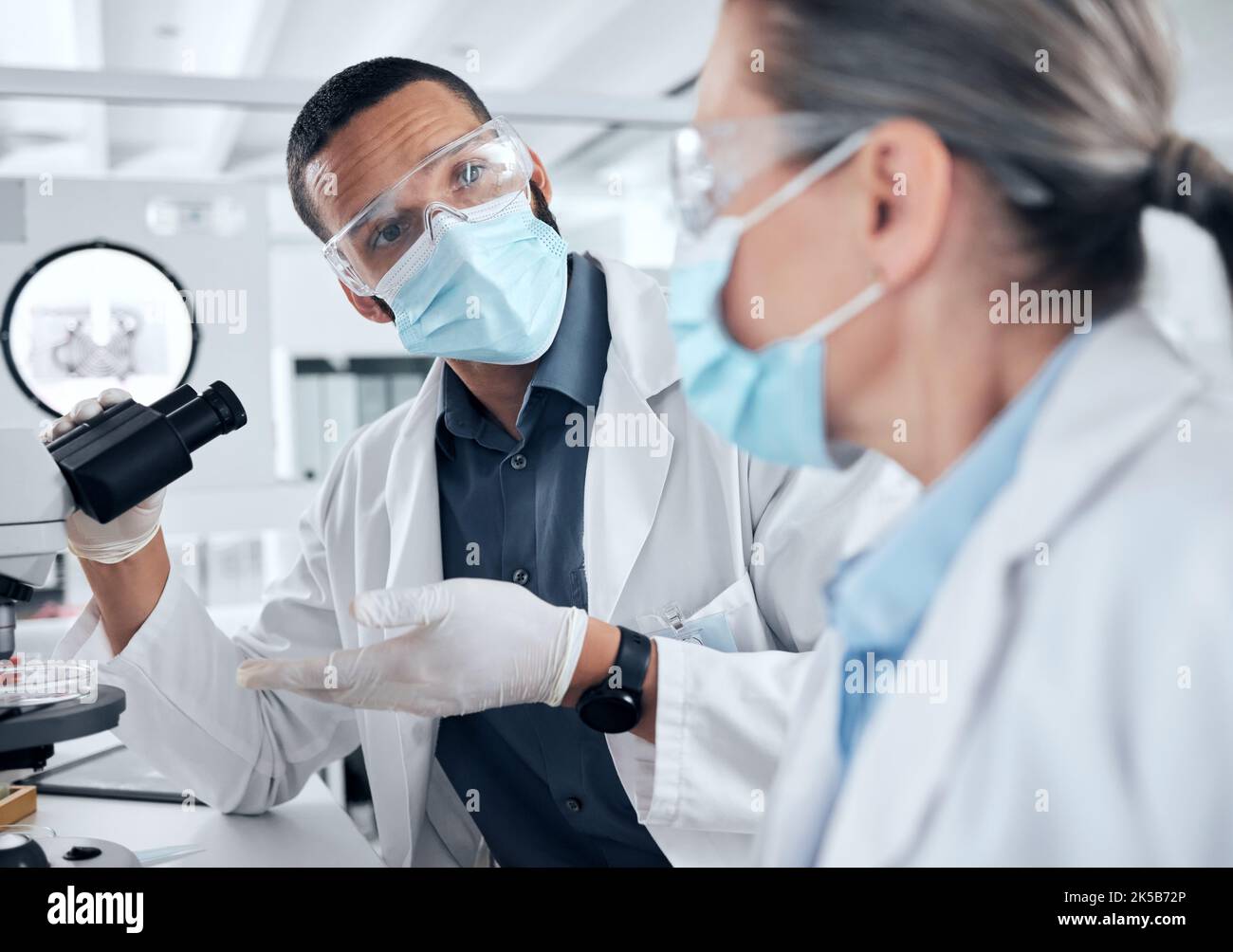 Gruppo di scienziati, microscopio e analisi di covid in un laboratorio di ricerca o di scienza per studiare il virus per la sicurezza, medicina o cura medica. Uomo e donna Foto Stock