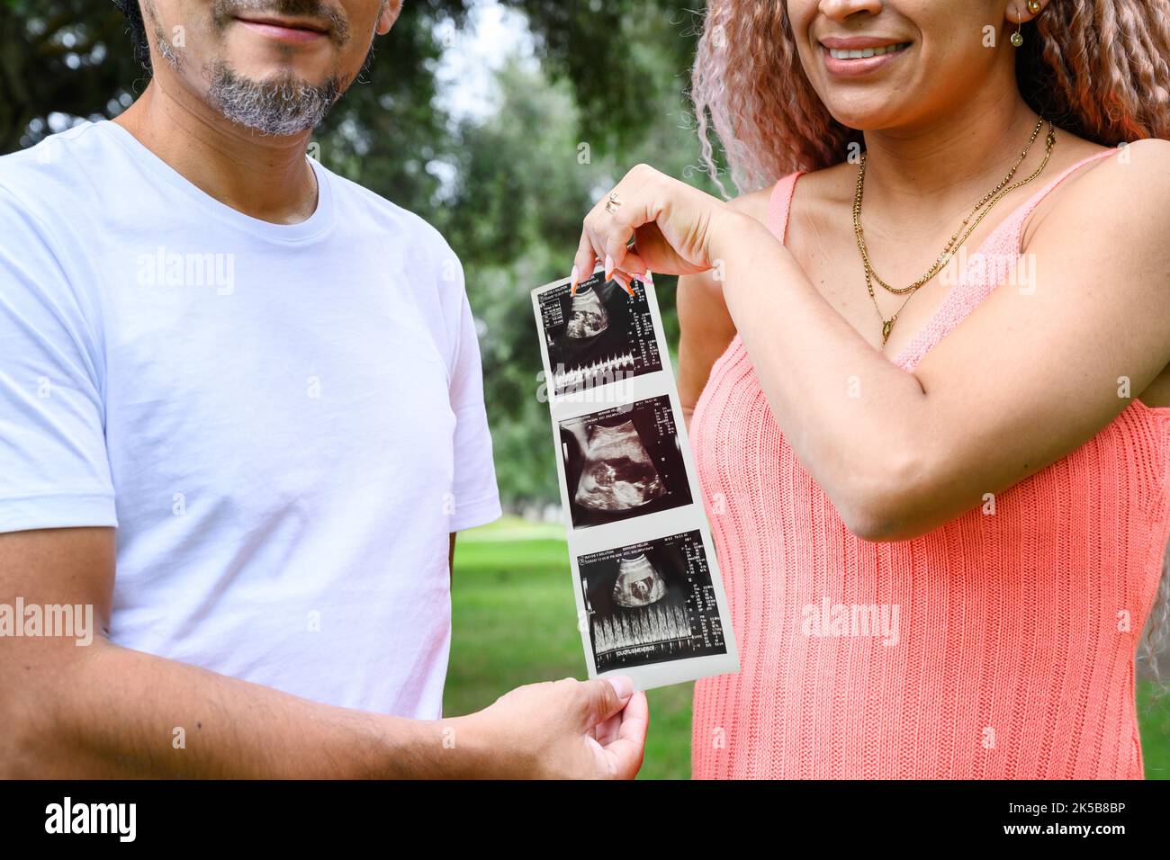 Coppia che tiene gli ultrasuoni all'aperto e che annuncia la gravidanza Foto Stock