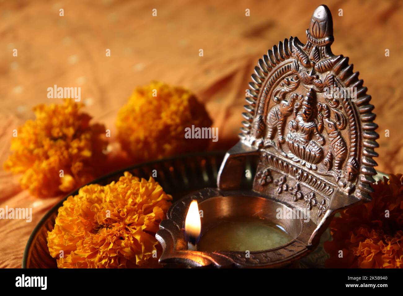 Olio di ottone illuminato dea Lakshmi /Gajalakshmi vilakku in una piastra di rame con fiori di marigold/Diwali/Deepavali festival Foto Stock