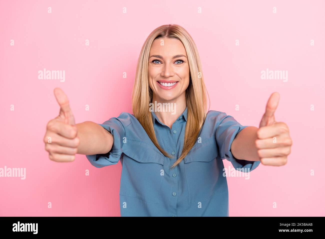 Primo piano foto di giovane adorabile carino bella donna d'affari indossare blusa blu mostrando pollici in su come nuovo posto vacante isolato su sfondo di colore rosa Foto Stock
