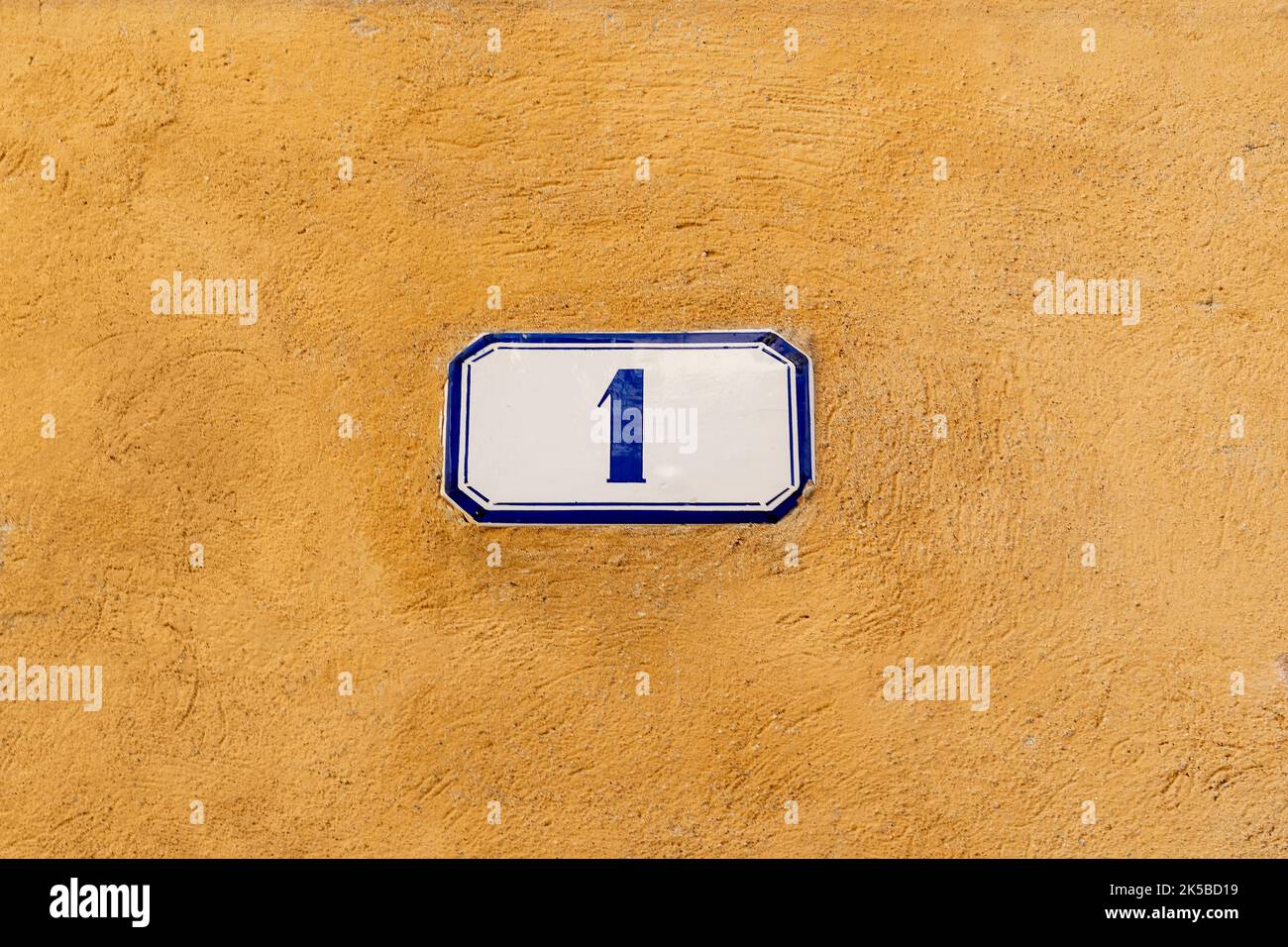 Numero di porta numero uno sulla lastra di smalto sulla parete di intonaco Foto Stock