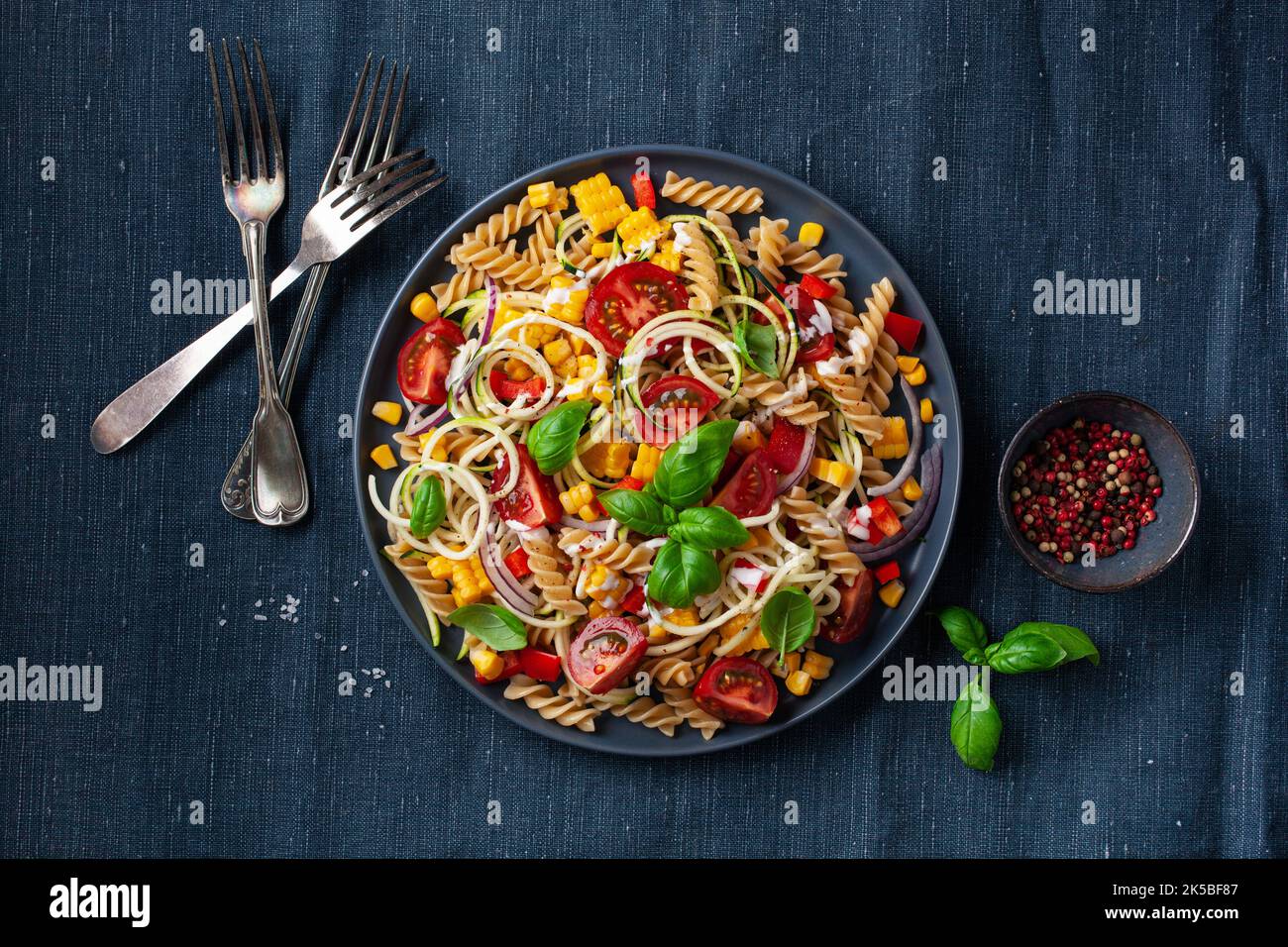 insalata di pasta sana con zucchine, mais dolce, pomodoro e basilico, pranzo vegetariano Foto Stock