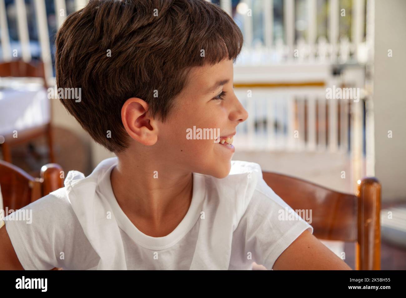 Ragazzo sorridente seduto in sedia guardando lontano Foto Stock