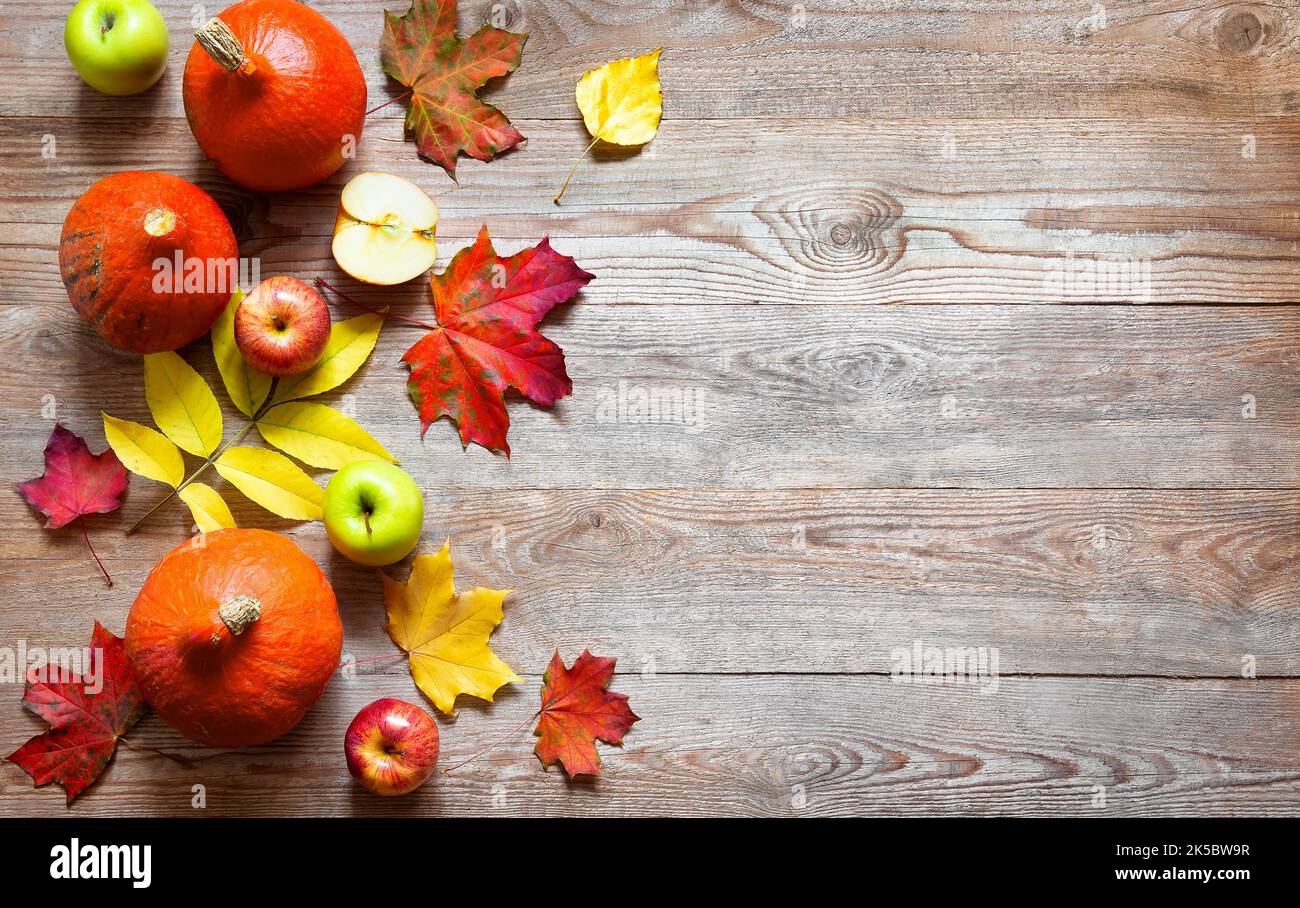 Autunno bordo da mele, zucca e foglie cadute su vecchio tavolo di legno. Halloween o concetto di giorno di ringraziamento. Zucca di ringraziamento con frutta. FRU Foto Stock