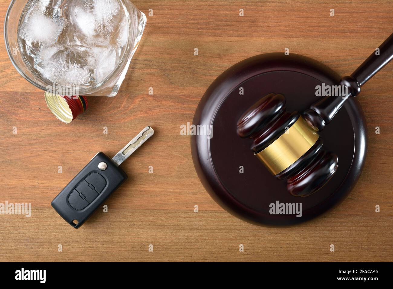 Gavel, chiave auto e vetro con alcool su tavolo di legno e sfondo nero isolato. Prova concettuale per la guida con tasso di alcool non consentito. Vista dall'alto Foto Stock