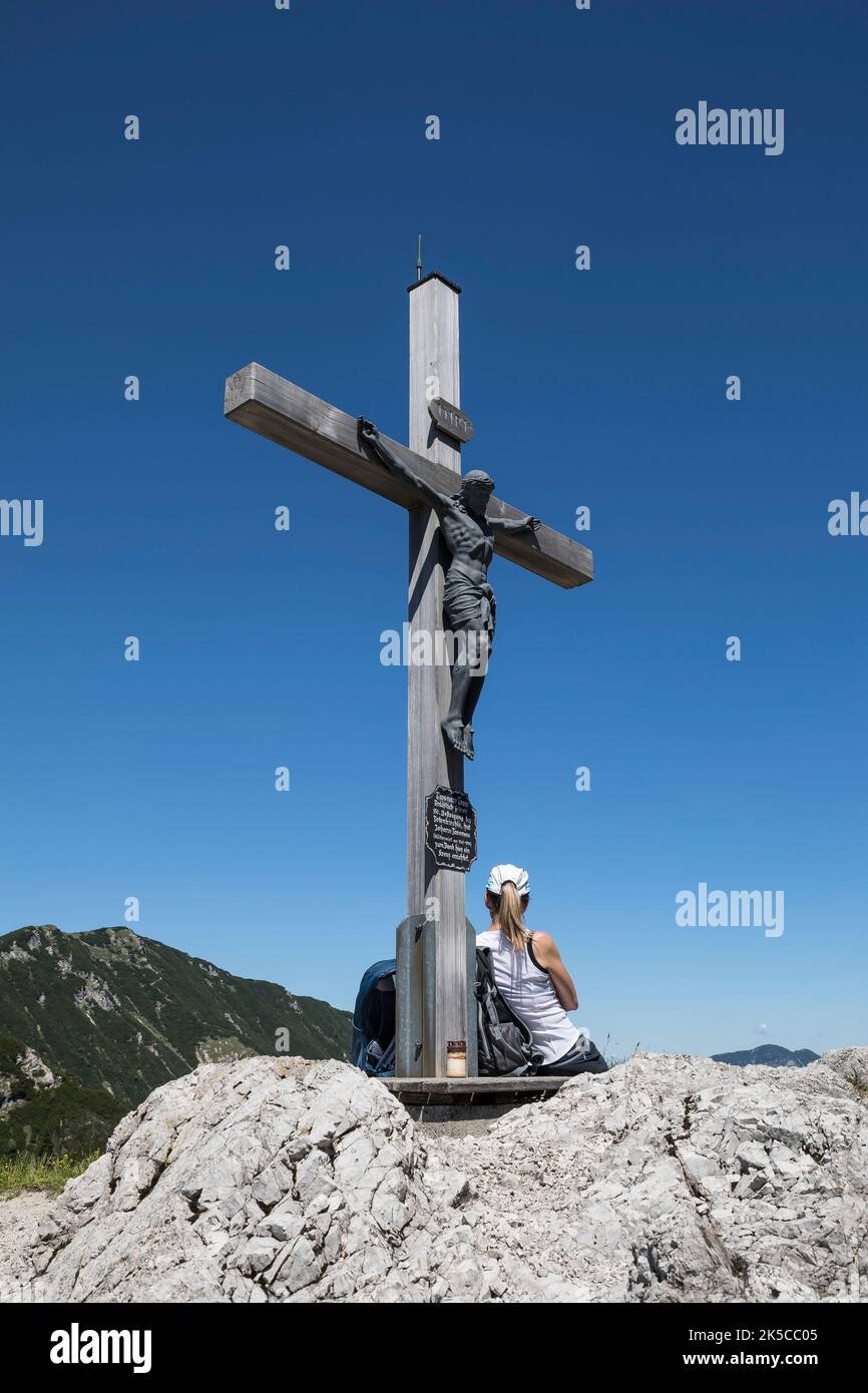 Una donna che riposa alla croce di Tavonaro, croce sommitale a Stripsenjoch, Kaisergebirge, Tirolo, Austria Foto Stock