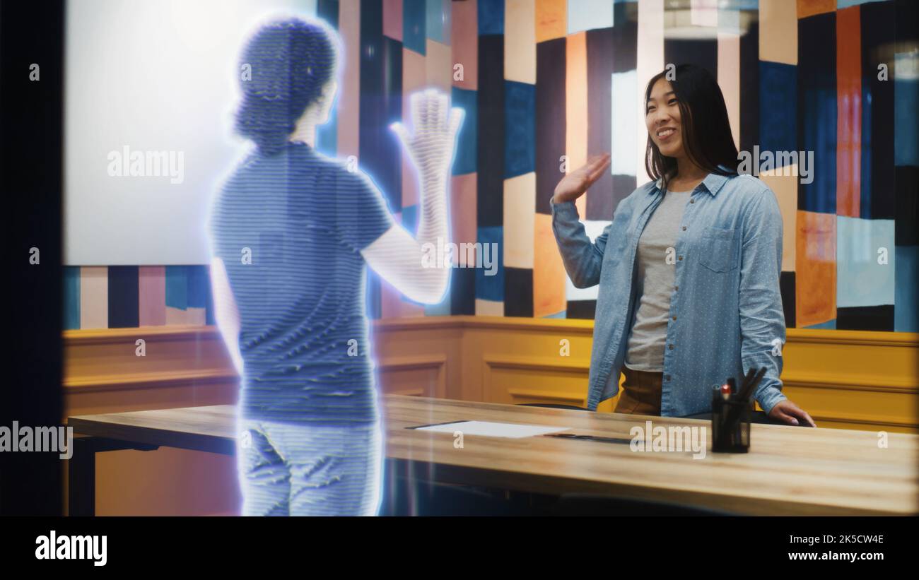 La donna asiatica parla alla chiamata con la sua amica utilizzando un software per la realtà aumentata. Ologramma della sua amica appare davanti a lei che riceve la chiamata. Effetti speciali VFX. Concetto di tecnologia futuristica. Foto Stock