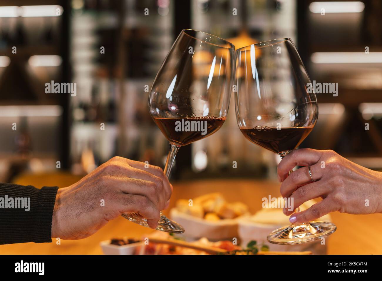 Una coppia romantica si siede l'una di fronte all'altra al tavolo da pranzo nella sala dei vini, si siede davanti ai bicchieri e sorseggia vino bianco Foto Stock