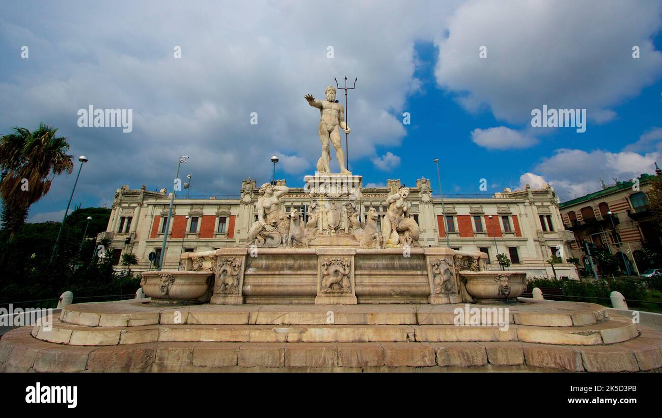 Sicilia, Messina, centro storico, fontana del Nettuno, grandangolo, fontana intera, edificio storico sullo sfondo, cielo nuvoloso blu Foto Stock