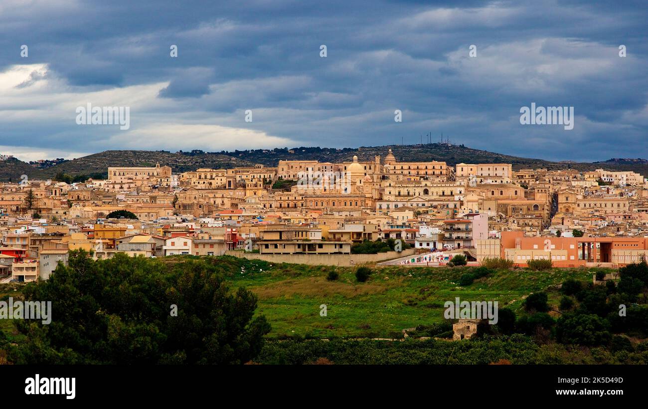 Italia, Sicilia, angolo barocco, città barocca, noto, architettura barocca, vista generale della città, cielo nuvoloso, luce soffusa, prati verdi in primo piano Foto Stock