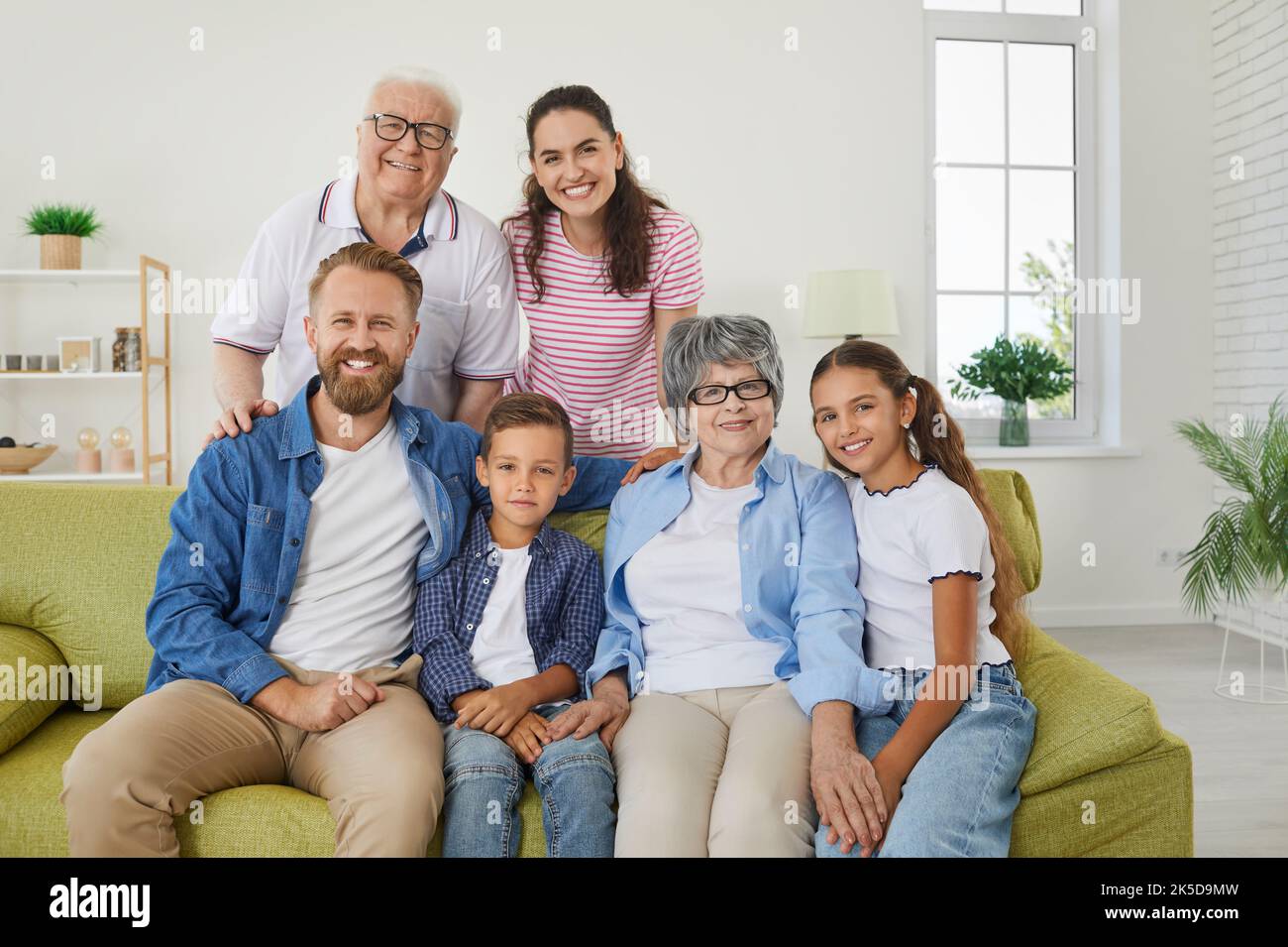 Allegro famiglia felice di tre generazioni in posa per la famiglia immagine seduta sul divano in soggiorno Foto Stock