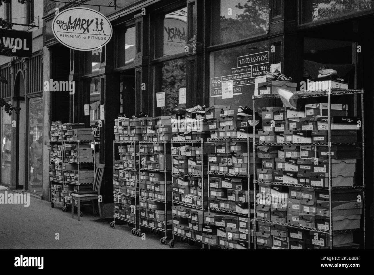 Le sneakers si accatastano su file di scaffalature accanto a un negozio di scarpe al Lowell Folk Festival nella storica Lowell, Massachusetts. L'immagine è stata acquisita in nero Foto Stock