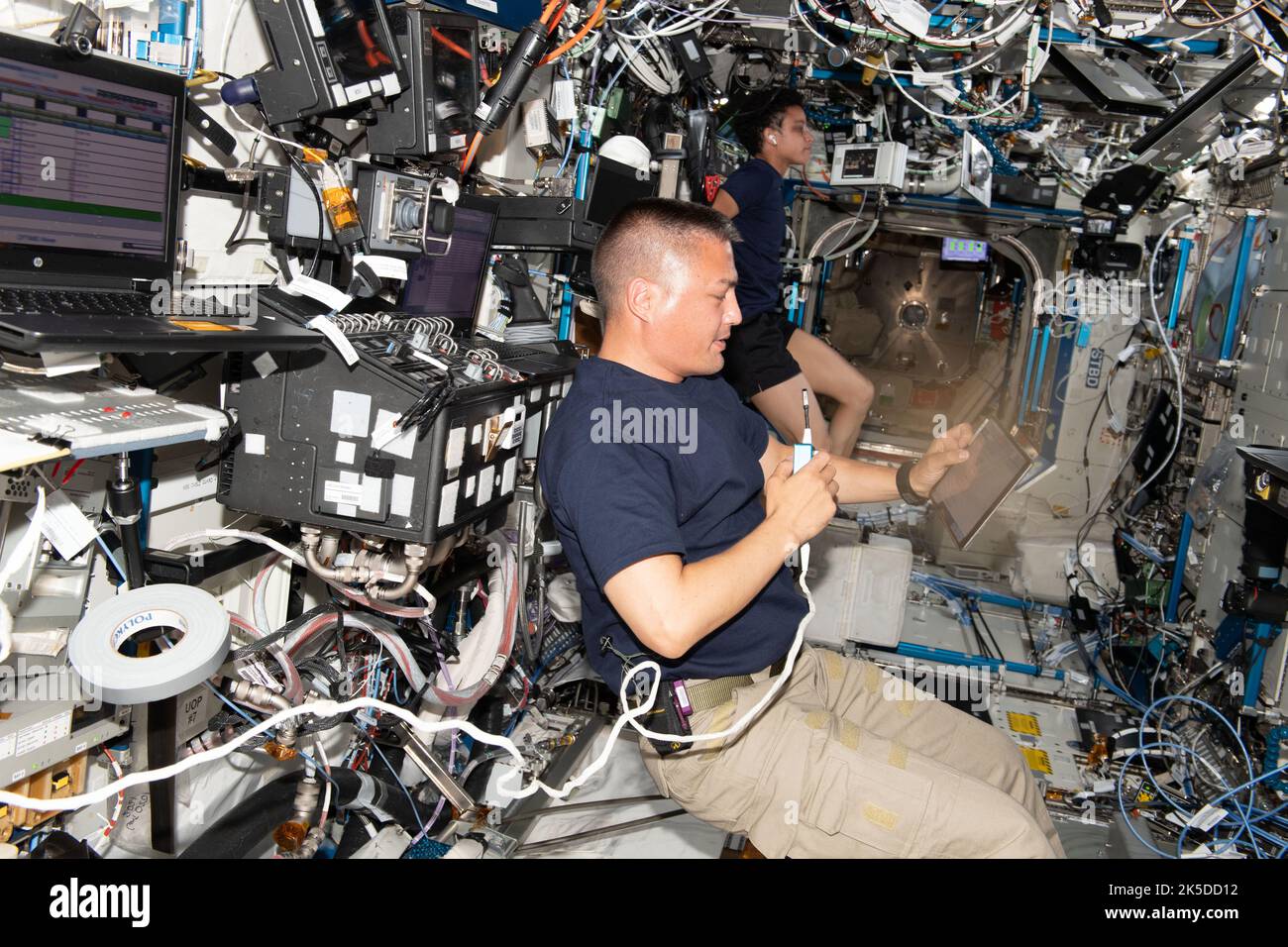 Expedition 67 gli ingegneri di volo Kjell Lindgren e Jessica Watkins, entrambi astronauti della NASA, sono raffigurati lavorando su attività separate all'interno del laboratorio del destino degli Stati Uniti della Stazione spaziale Internazionale. Lindgren esamina il rendezvous e le procedure di attracco su un tablet touchscreen il giorno prima dell'arrivo della nave d'equipaggio Starliner della Boeing CST-100. Watkins si occupa di un ciclo di esercizio, noto anche come Cycle Ergometer with Vibration Isolation and Stabilization (Ergometro a ciclo con isolamento e stabilizzazione delle vibrazioni) o CEVIS. Foto Stock