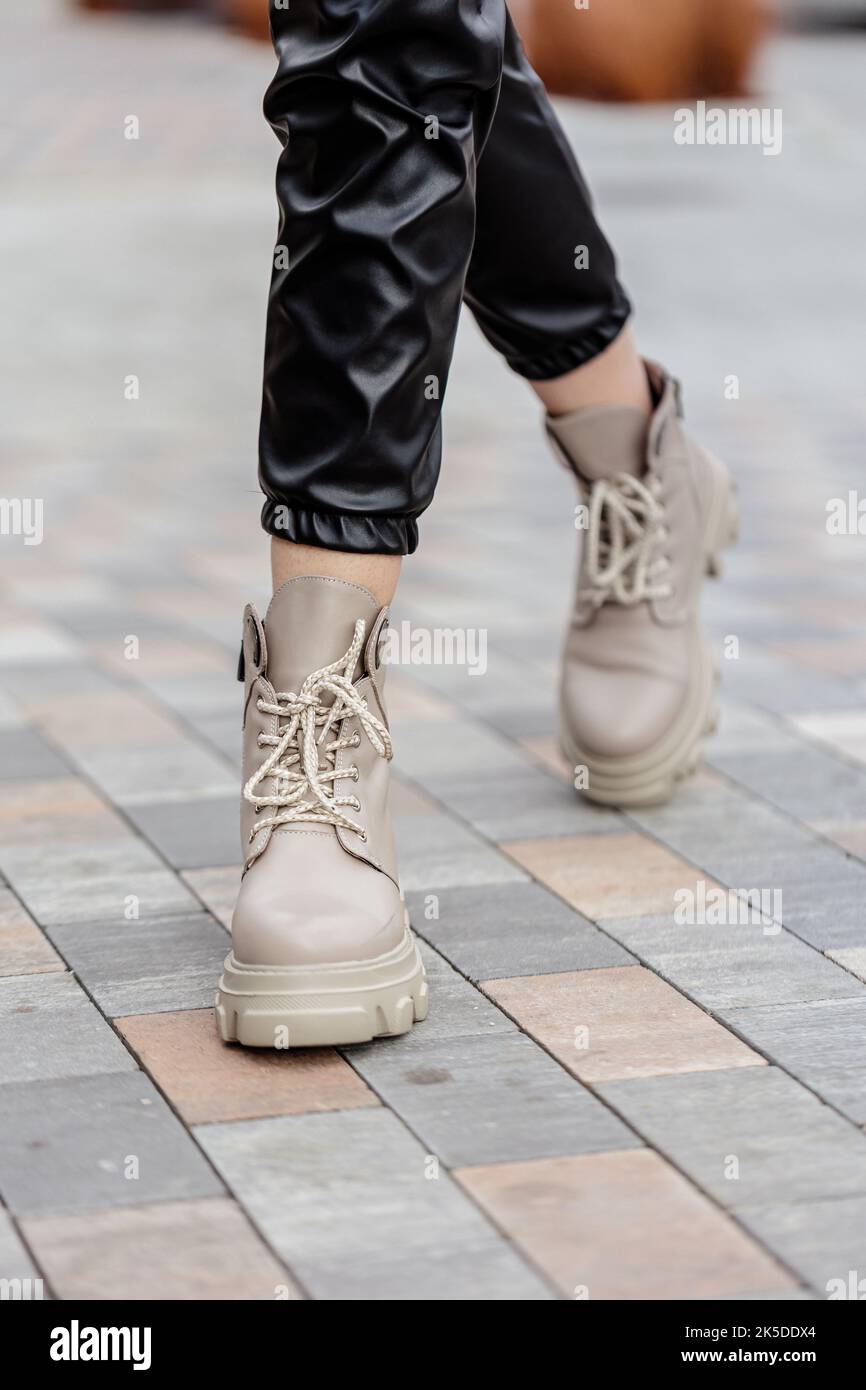 Donna elegante stand in scarpe beige. Primo piano delle gambe femminili in eleganti stivali in pelle beige vintage. Nuova collezione stagionale di scarpe da donna Foto Stock