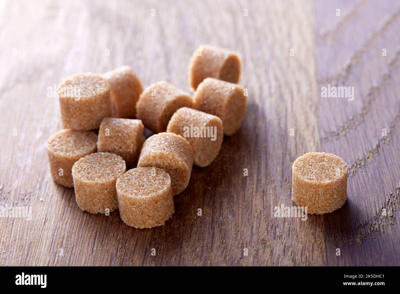 Lo zucchero rotondo marrone si forma su un vecchio tagliere di legno scuro - vista ravvicinata Foto Stock