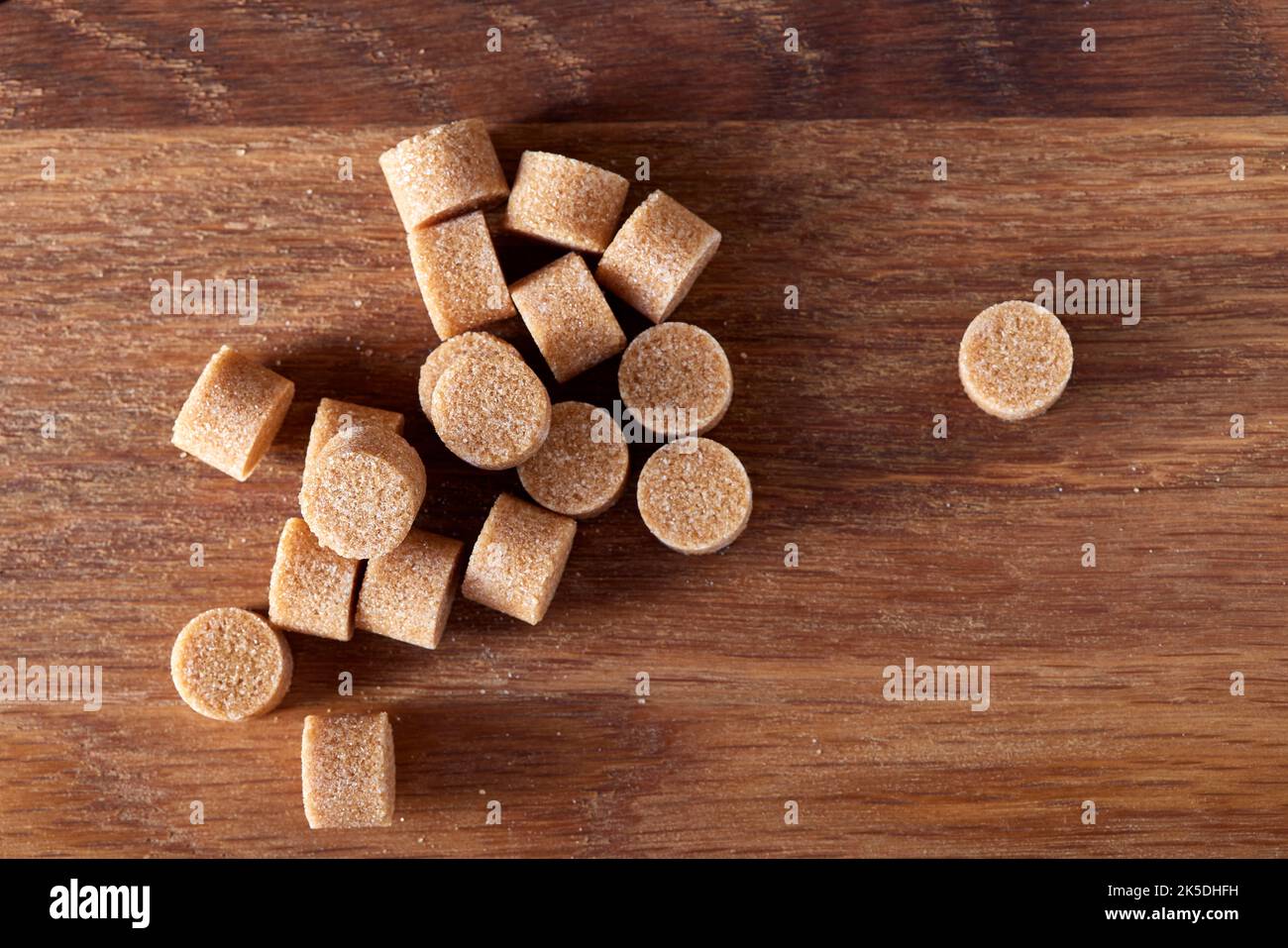 Lo zucchero rotondo marrone si forma su un vecchio tagliere di legno scuro - vista dall'alto Foto Stock