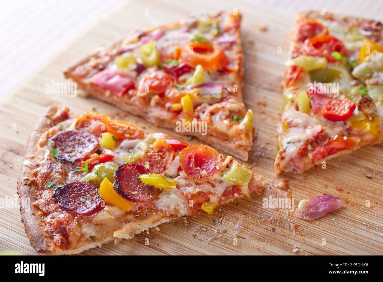 Pizza con salame, peperoni, pomodori e cipolle su un tavolo - vista ravvicinata Foto Stock