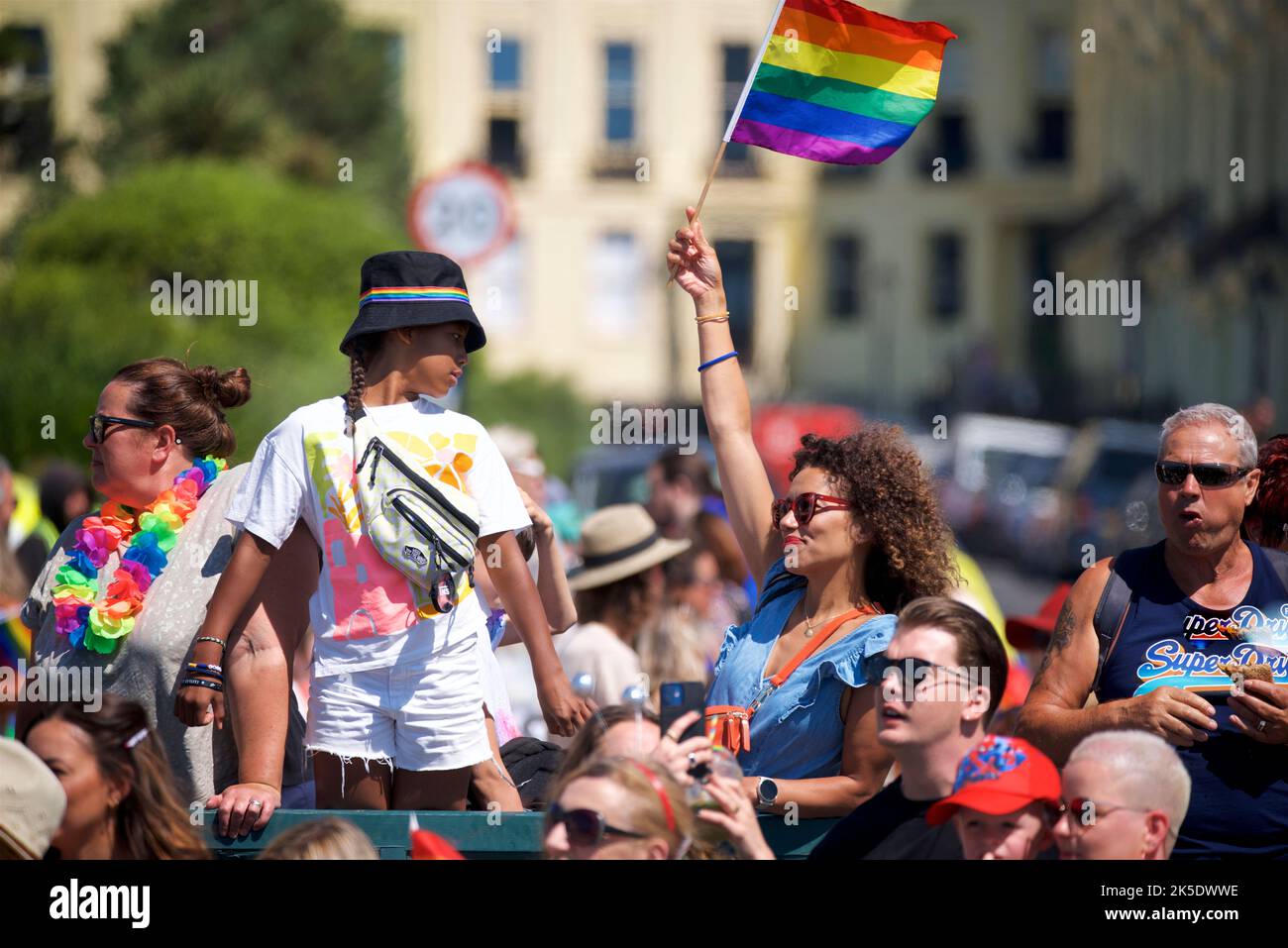 Brighton & Hove Pride Festival, Brighton & Hove, East Sussex, Inghilterra. Spettatore che sventola la bandiera arcobaleno Foto Stock