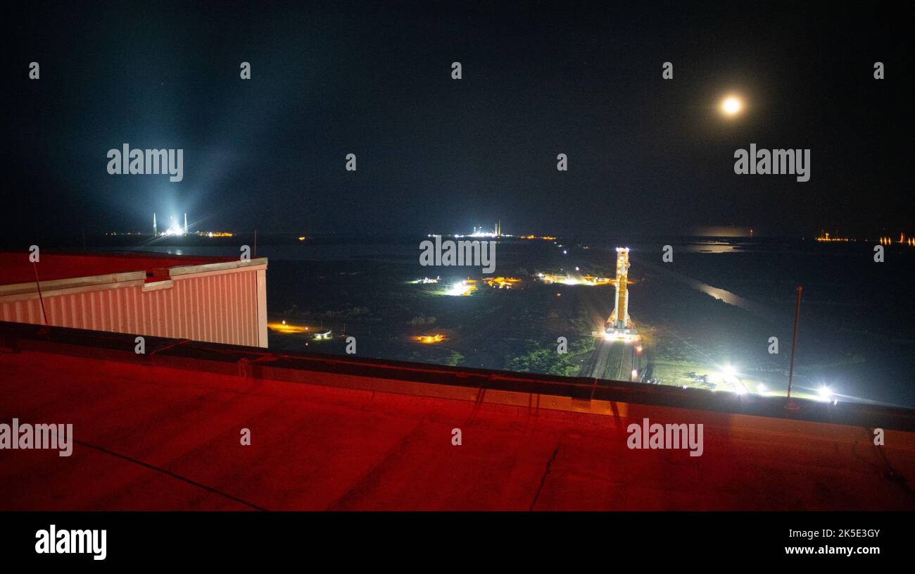 La Luna è vista dietro il razzo Space Launch System (SLS) della NASA con la navicella spaziale Orion a bordo è fuori in cima al lanciatore mobile dal Vehicle Assembly Building al Launch Pad 39B, mercoledì 17 agosto 2022, al Kennedy Space Center della NASA in Florida. La missione Artemis i della NASA è il primo test integrato dei sistemi di esplorazione dello spazio profondo dell’agenzia: La navicella spaziale Orion, il razzo SLS e i sistemi di supporto a terra. Il lancio del test di volo senza equipaggio è previsto per non più del 29 agosto. Foto Stock