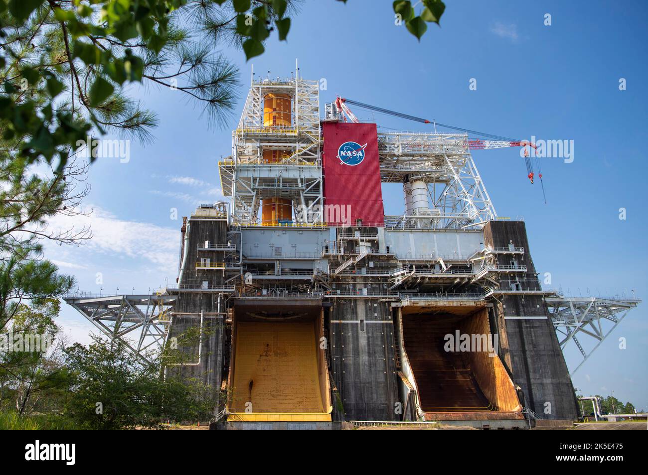 Lo Space Launch System (SLS) completa il test Green Run per il palcoscenico principale del razzo, installato in alto a sinistra dello Stand di prova B-2 presso lo Stennis Space Center della NASA vicino a Bay St. Louis, Mississippi. Per Green Run, il team sta completando una serie di otto test che culminano con il Test 8, un test completo di incendio a caldo della durata di otto minuti. Le fiamme provenienti dal test fuoriescono dal secchio giallo indicato qui sul lato nord del banco di prova. Il core stage della SLS è in fase di test prima della missione lunare Artemis I. Versione ottimizzata di un'immagine NASA originale. Credito: NASA Foto Stock