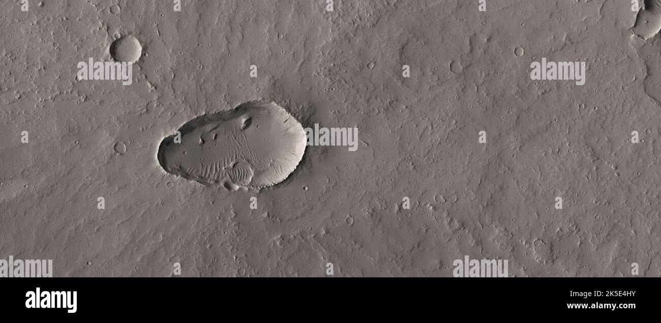 Ci sono molti vulcani scudo su Marte. La NASA è interessata ad acquisire immagini delle proprie regioni di ventilazione per comprendere i processi e cercare i segni delle attività recenti. Il vulcanismo attivo è una spiegazione per il gas metano che è stato rilevato nell'atmosfera di Marte. Questa immagine HiRISE mostra che la caldera sommitale è coperta da polvere e coperta da piccoli crateri d'impatto, quindi non c'è alcuna possibilità che questo vulcano sia stato attivo di recente abbastanza da influenzare i gas in traccia atmosferici correnti. L'immagine mostra un terreno di meno di 5km mm. Una versione ottimizzata e unica delle immagini NASA. Credit: ASA/JPL/UArizona Foto Stock