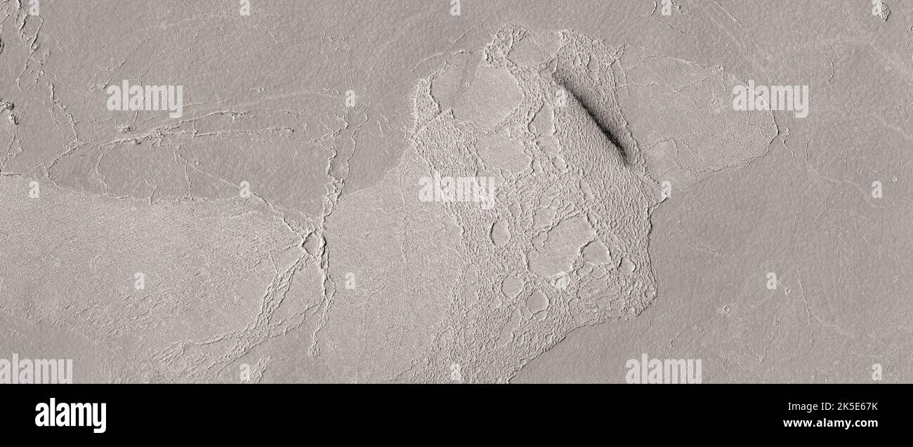 Paesaggio marziano. Questa immagine HiRISE mostra parte della pianura lavica alluvionale di Athabasca Valles, il più grande flusso lavico più giovane sulla superficie di Marte. In questa posizione, ci sono due pezzi di crosta di lava con strane proprietà infrarosse. Rispetto al resto del flusso lavico, queste due aree sopraelevate sono fredde di notte e calde di giorno. Questa proprietà della superficie, dove la temperatura cambia rapidamente, è chiamata "bassa inerzia termica". Le rocce tendono ad avere un'inerzia termica relativamente elevata, quindi questo è inaspettato. Una versione ottimizzata e unica delle immagini NASA. Credit: ASA/JPL/UArizona Foto Stock