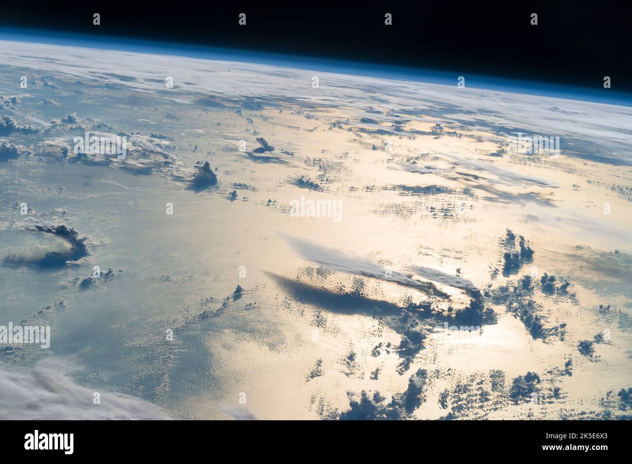 Volando sopra il Mare delle Filippine, un astronauta guardò verso l'orizzonte dalla Stazione spaziale Internazionale e sparò questa fotografia di nuvole tridimensionali, la sottile busta blu dell'atmosfera e il nero dello spazio. La luce solare del tardo pomeriggio illumina un'ampia striscia della superficie del mare sul lato destro dell'immagine. In lontananza, un ampio strato di nuvole oscura principalmente le isole Filippine settentrionali (in alto a destra). Una versione unica di un'immagine originale della NASA. Credito: NASA Foto Stock