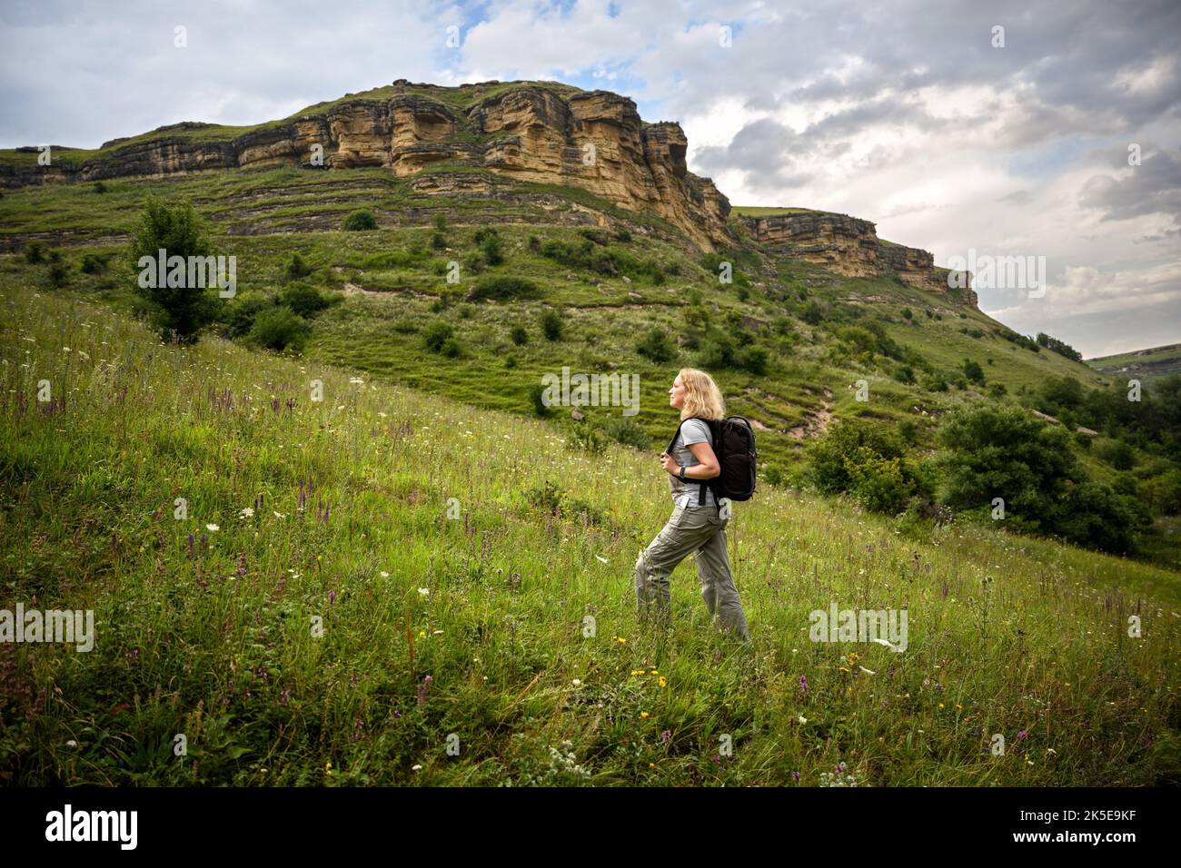 Ragazza viaggiatore in montagna, donna escursionista in salita, giovane turista cammina da solo nel parco nazionale in estate. Concetto di escursione, avventura, nat selvaggio Foto Stock