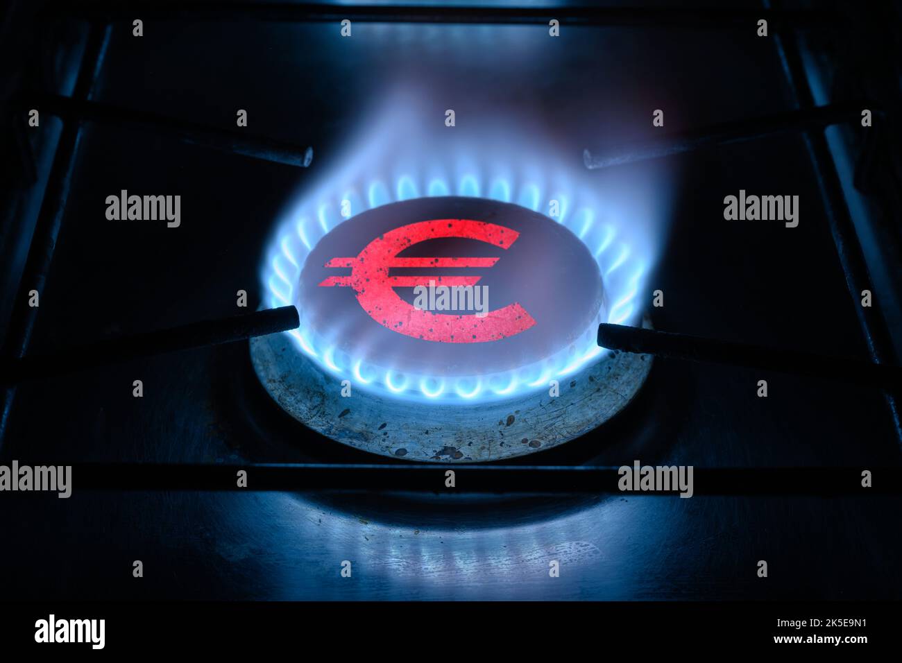 Bruciatore ad anello a gas e segno euro, simbolo di denaro europeo sulla stufa a gas di casa. Fiamma e valuta al propano blu. Concetto di crisi energetica, economia europea, petrolio Foto Stock