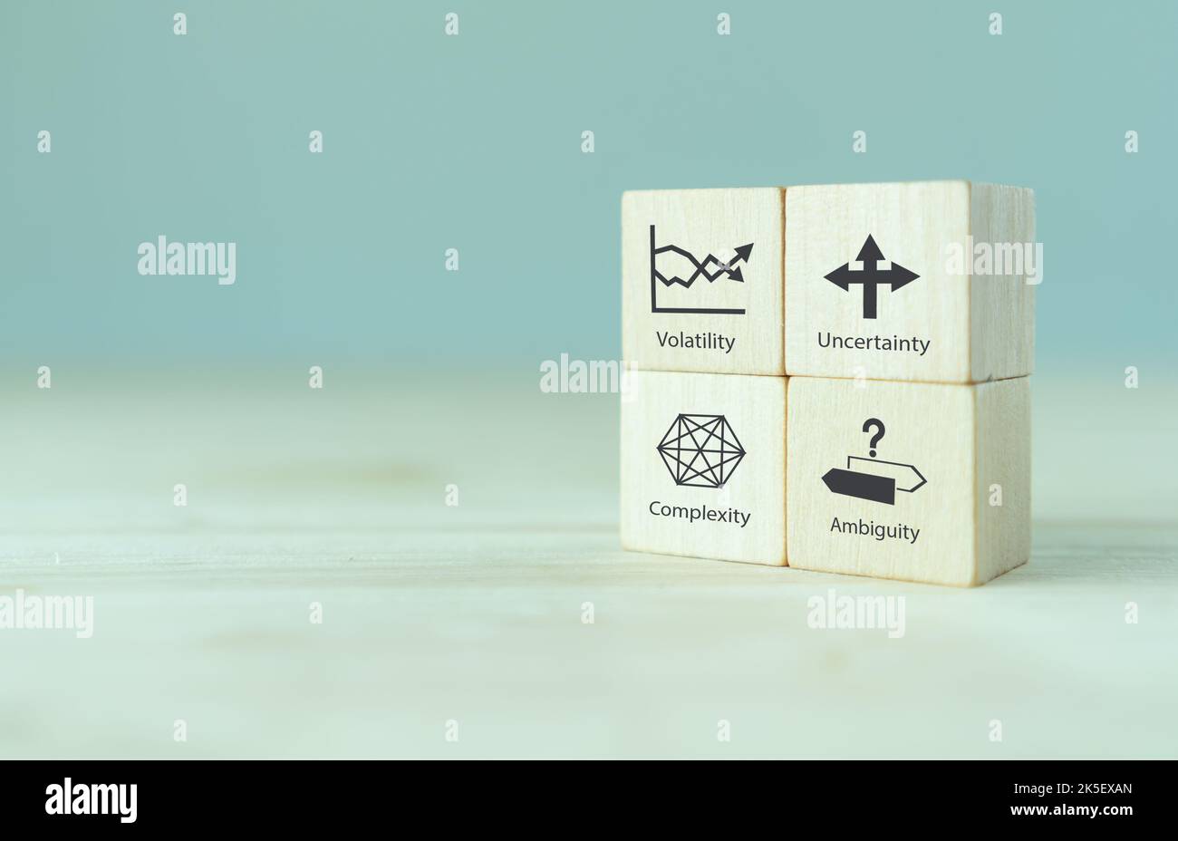 VUCA e gestione strategica. Cubi di legno con icona e testo VUCA; volatilità, incertezza, complessità, ambiguità con sfondo grigio. Gestione intelligente Foto Stock