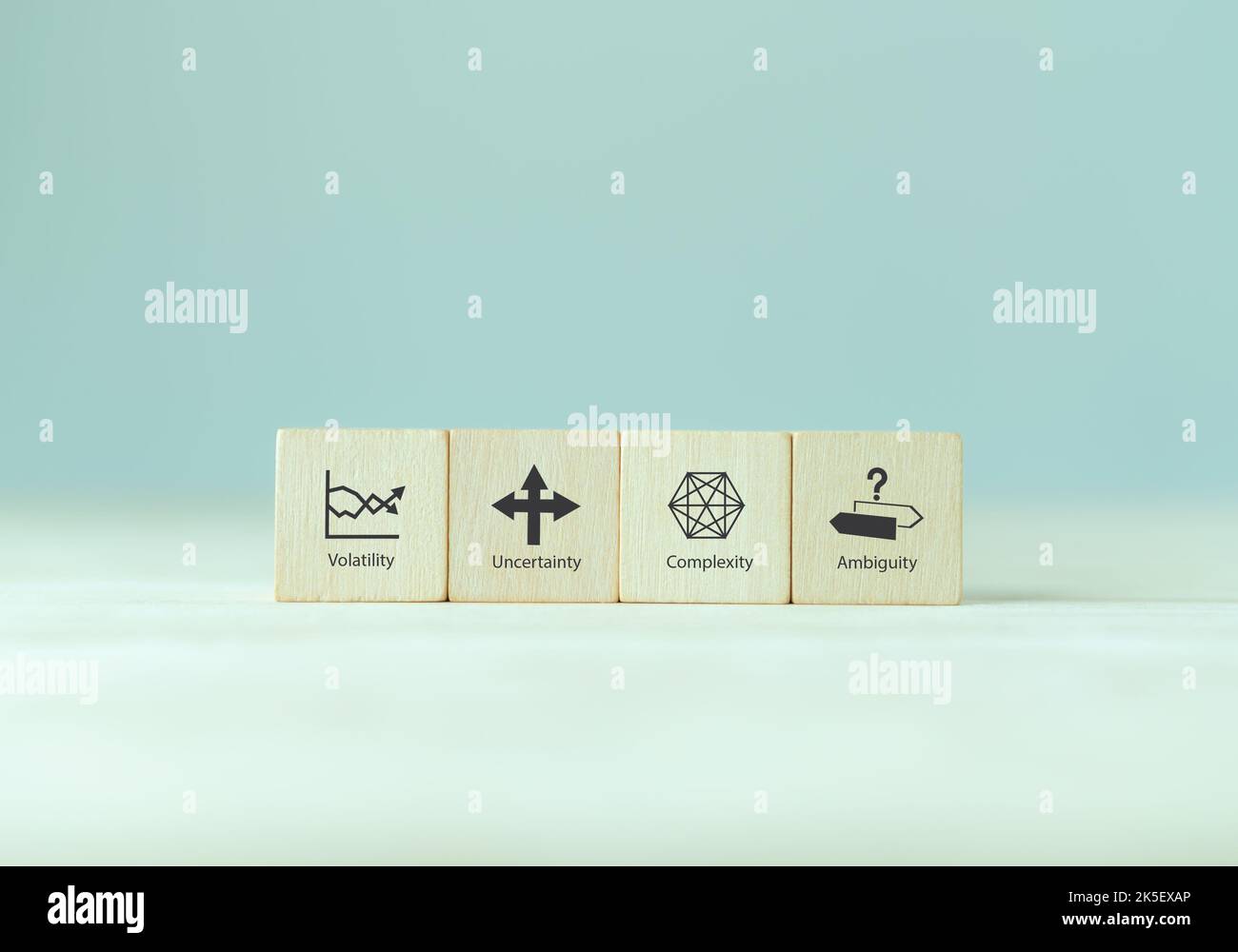 VUCA e gestione strategica. Cubi di legno con icona e testo VUCA; volatilità, incertezza, complessità, ambiguità con sfondo grigio. Gestione intelligente Foto Stock
