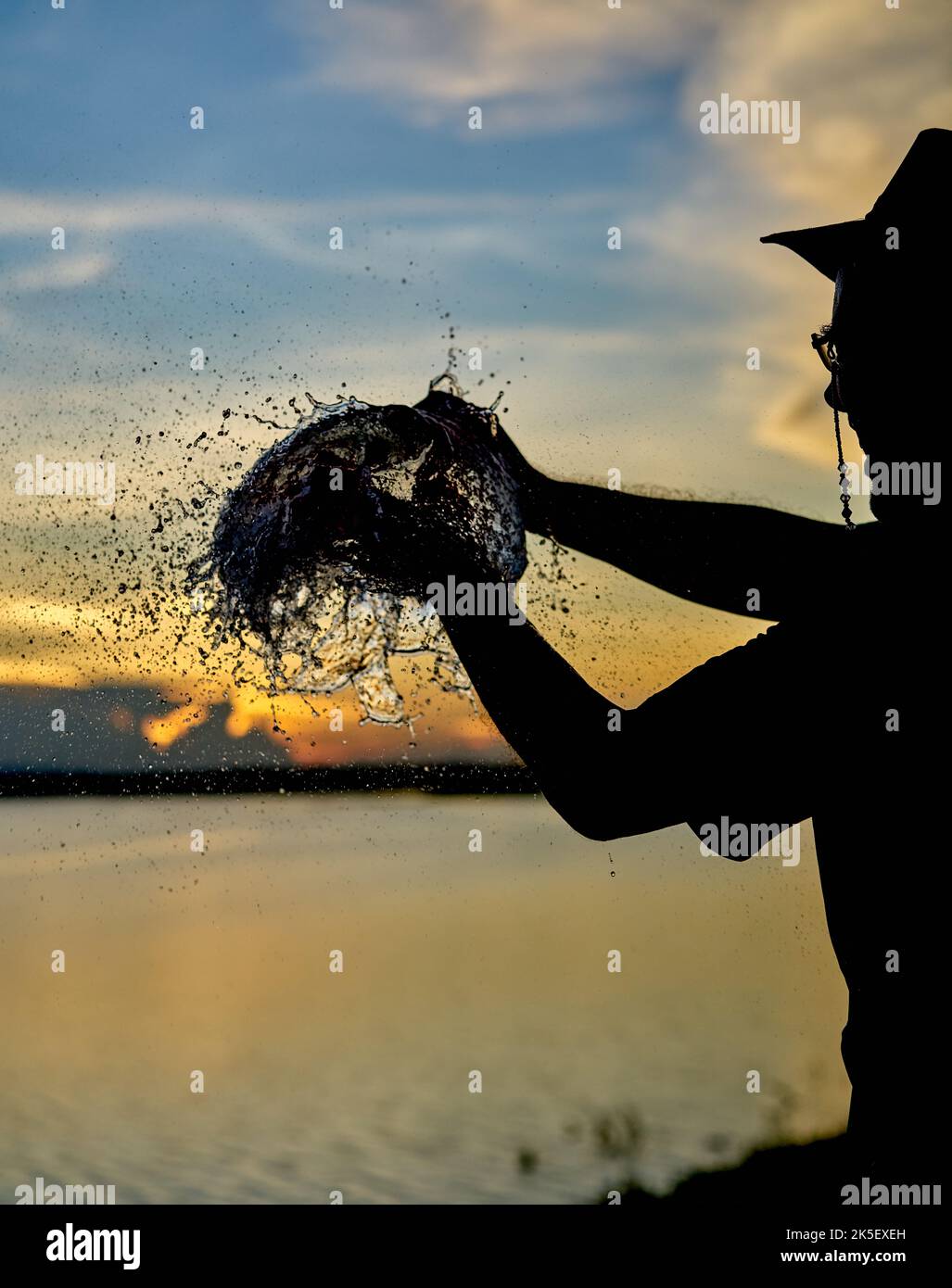 Un pallone d'acqua che scoppierà contro un cielo al tramonto. Foto Stock