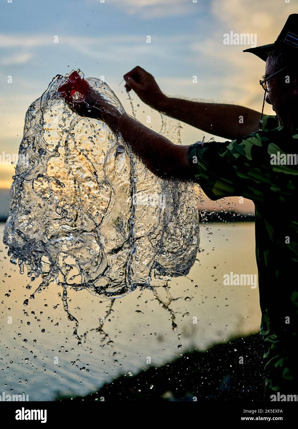 Un pallone d'acqua che scoppierà contro un cielo al tramonto. Foto Stock