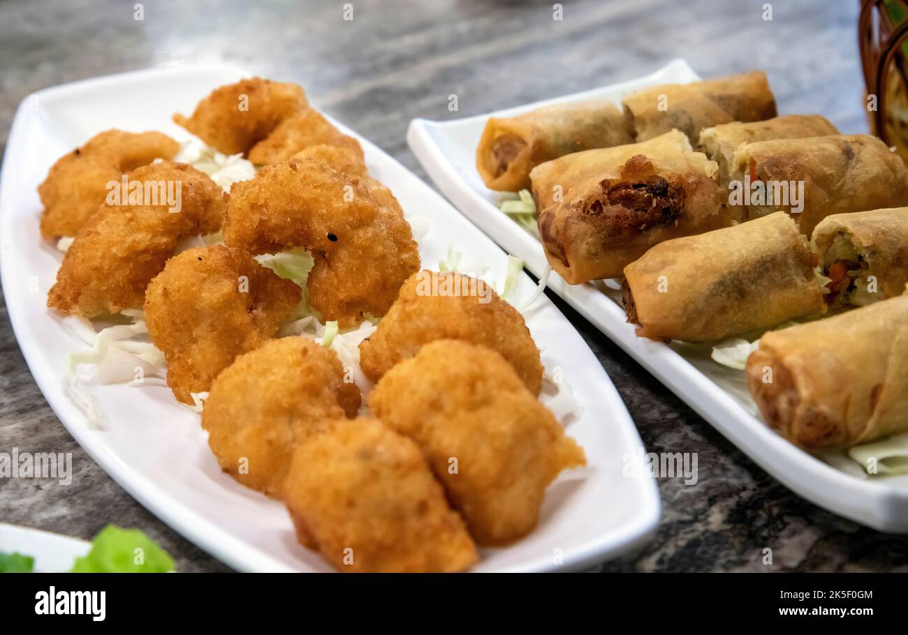 Torte di pesce tailandesi assortite e involtini primaverili. Foto Stock