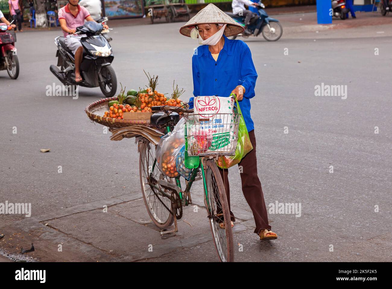 Venditore di strada che indossa cappello di bambù con bicicletta, Hai Phong, Vietnam Foto Stock