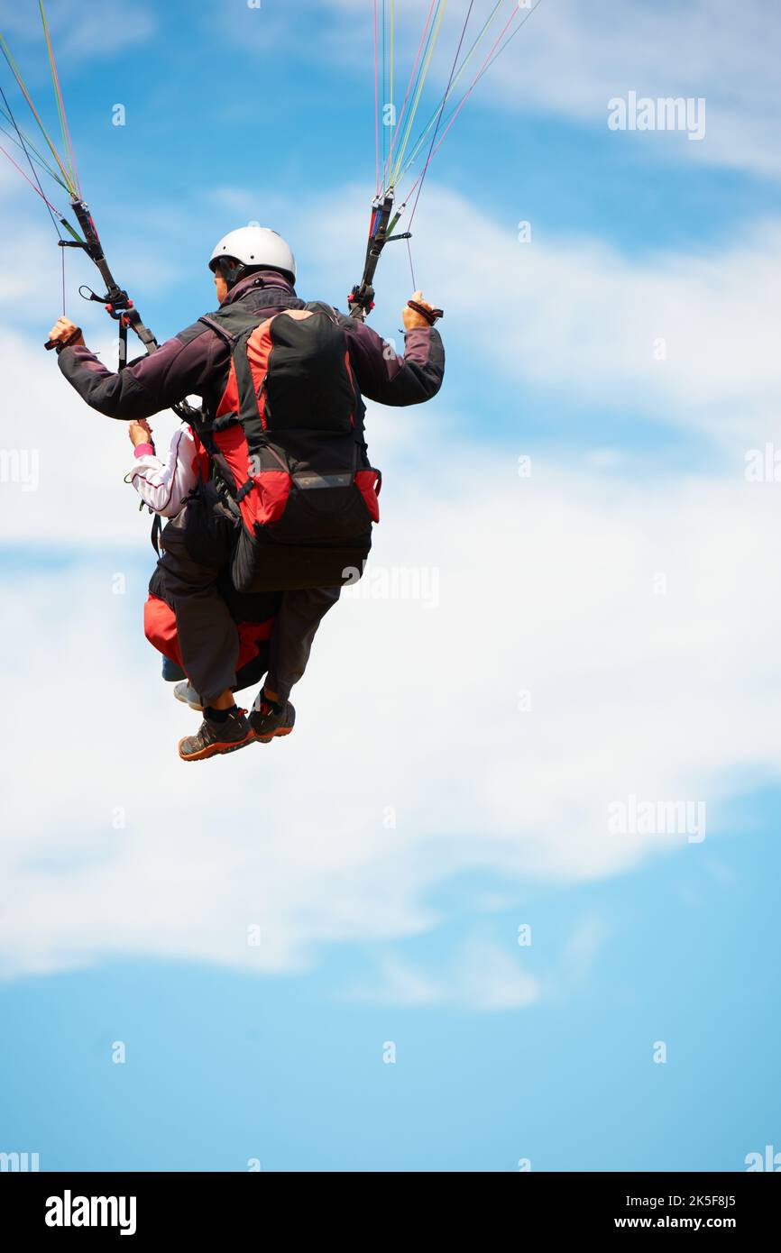 Vela nel cielo. Vista posteriore di due giovani che fanno parapendio in tandem. Foto Stock