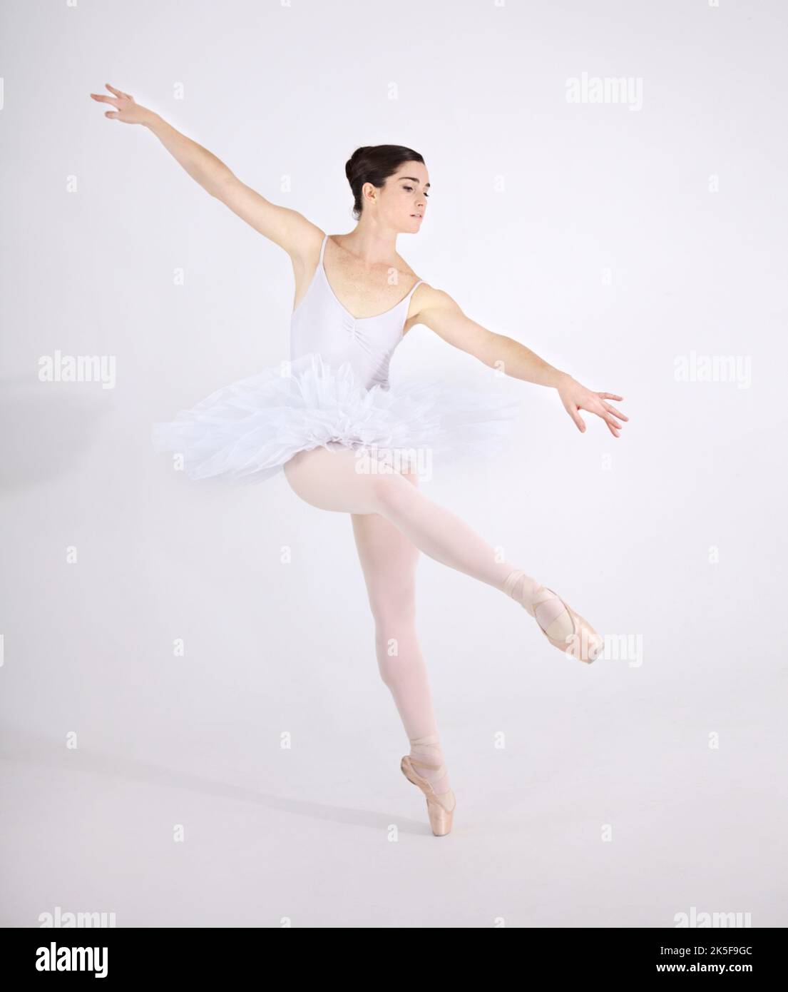 Perso nella danza. Ballerina giovane dedicata che balla en pointe su sfondo bianco. Foto Stock