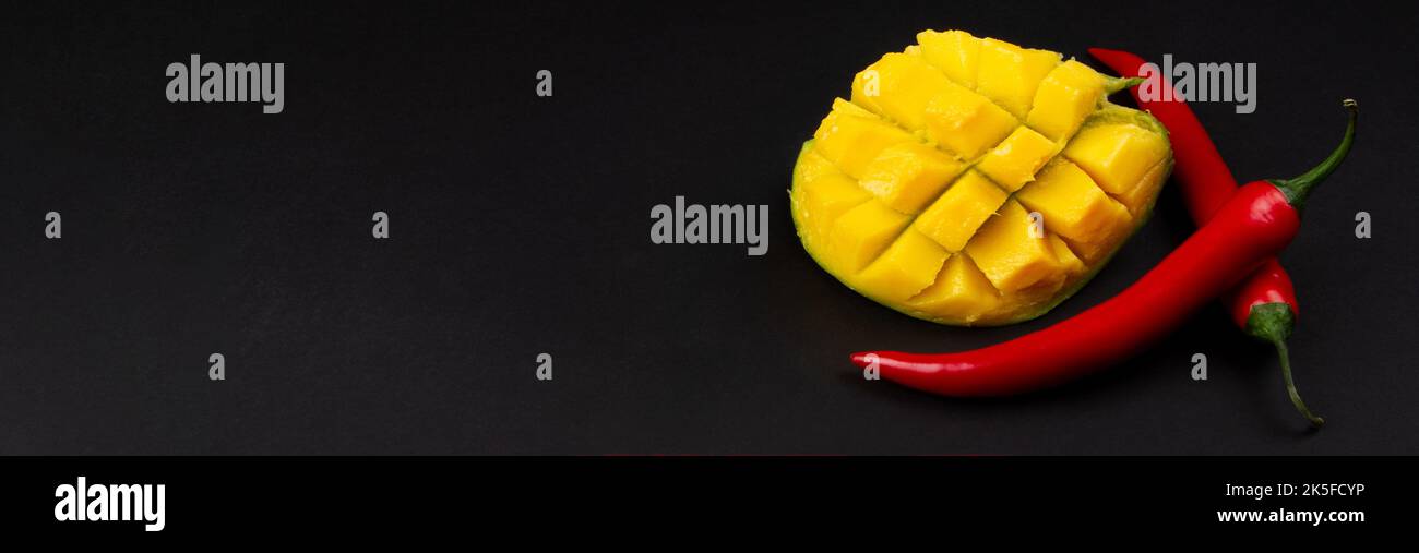 Mango a dadini e peperoncino intero su fondo scuro. Ingredienti per la salsa. Banner. Foto Stock