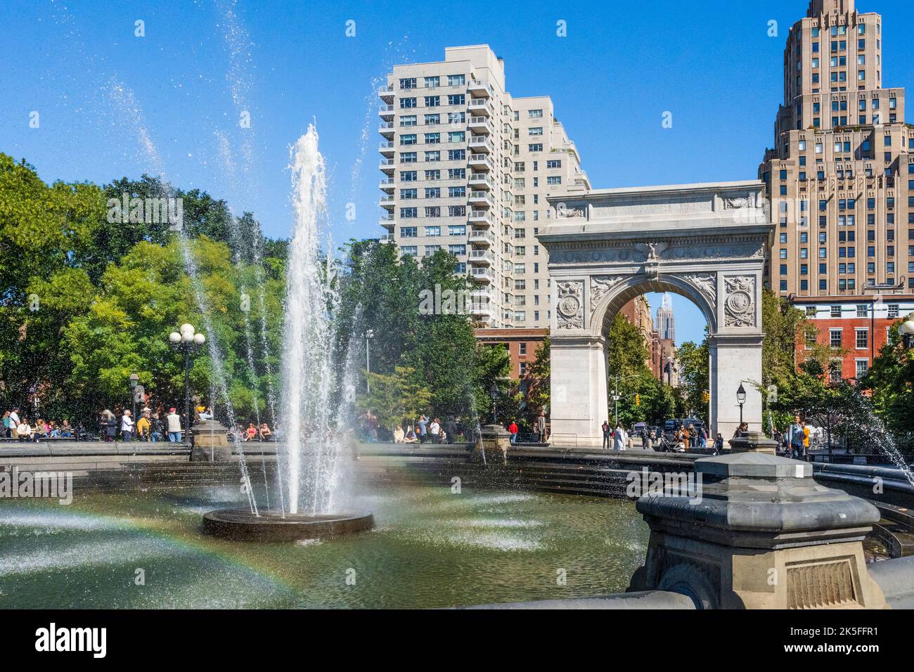 Washington Square Park, con turisti, fontana, arcobaleno nel bacino e Washington Square Arch sullo sfondo, New York City, USA Foto Stock